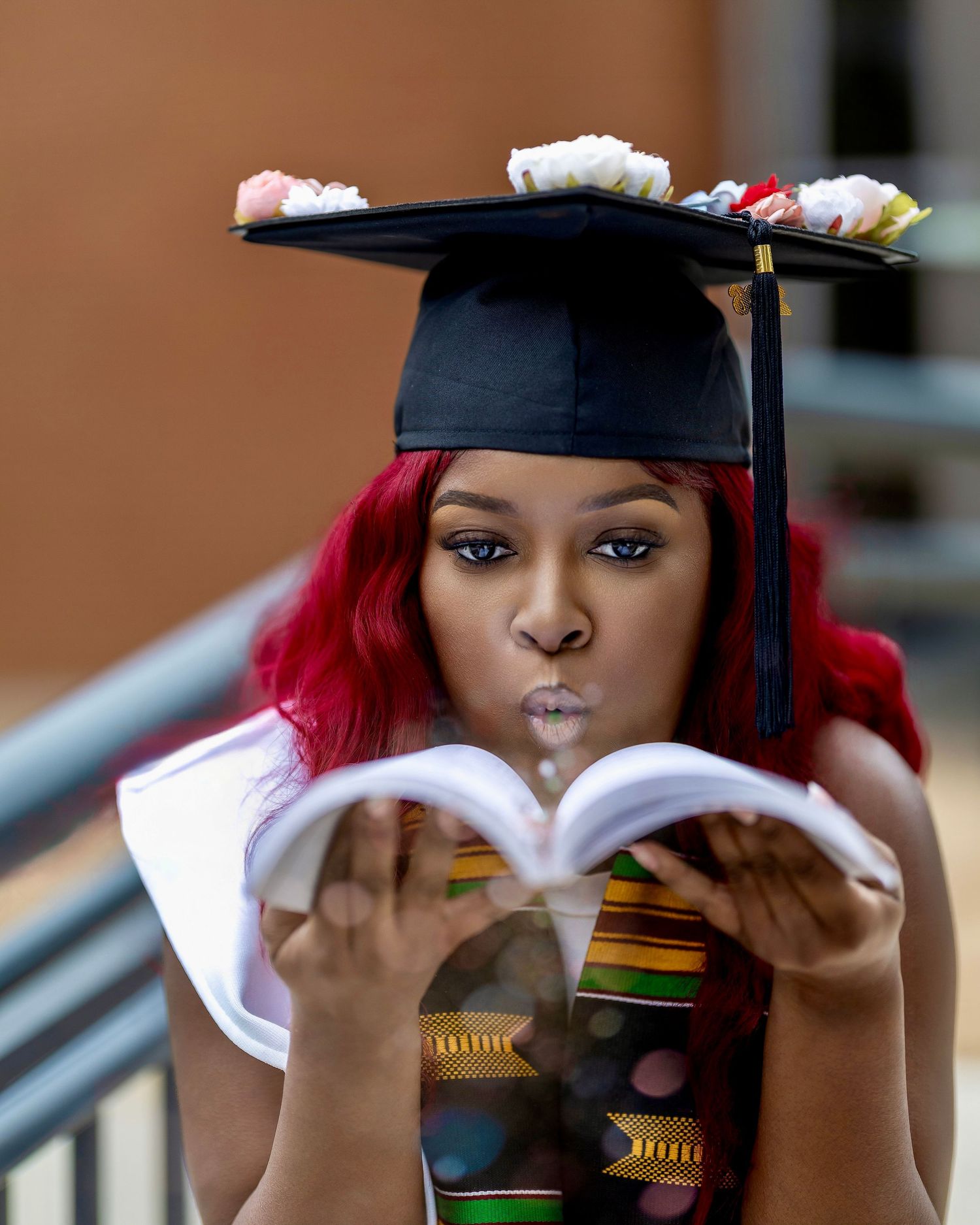 College graduate blowing a kiss over an open book while wearing a decorated graduation cap