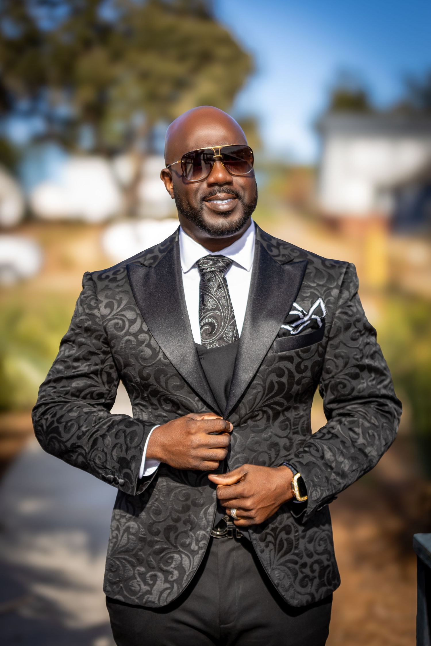 Man in a patterned suit and sunglasses posing in a stylish portrait setting