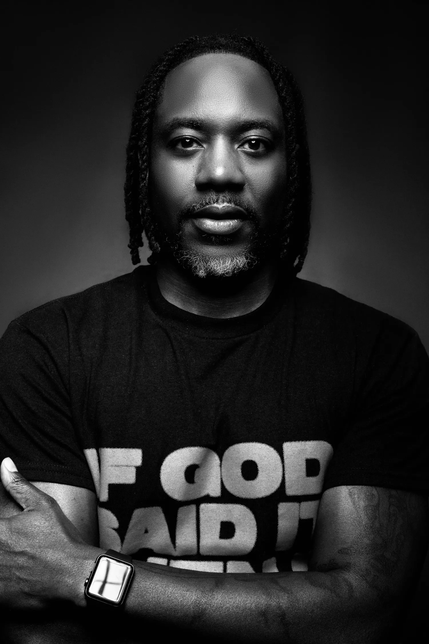 Black-and-white portrait of a photographer wearing a black T-shirt with folded arms
