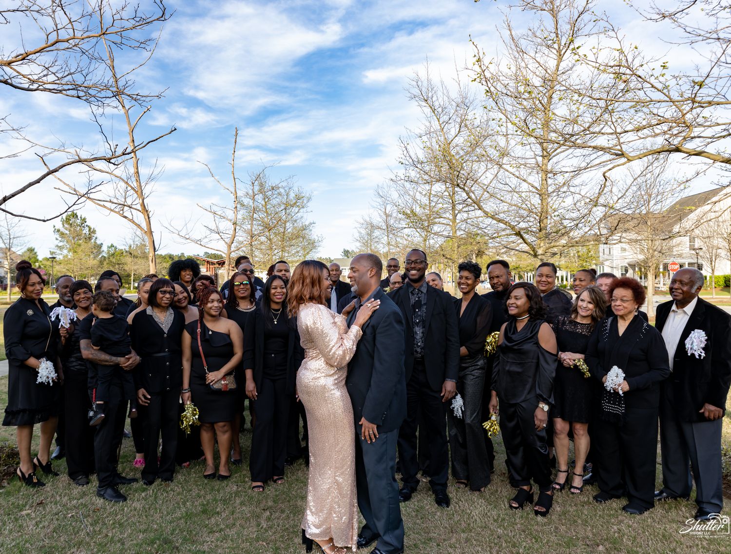 Large group gathered outdoors for a celebration photo with a couple standing in the center