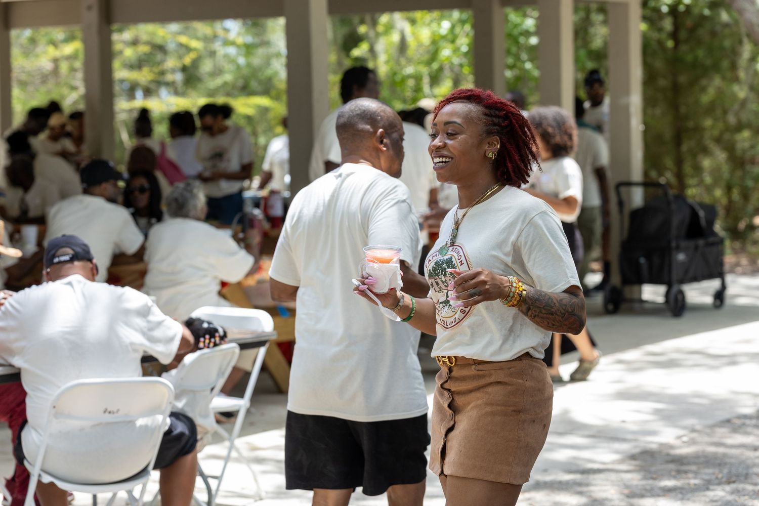 People socializing outdoors at a casual community gathering under a tent.