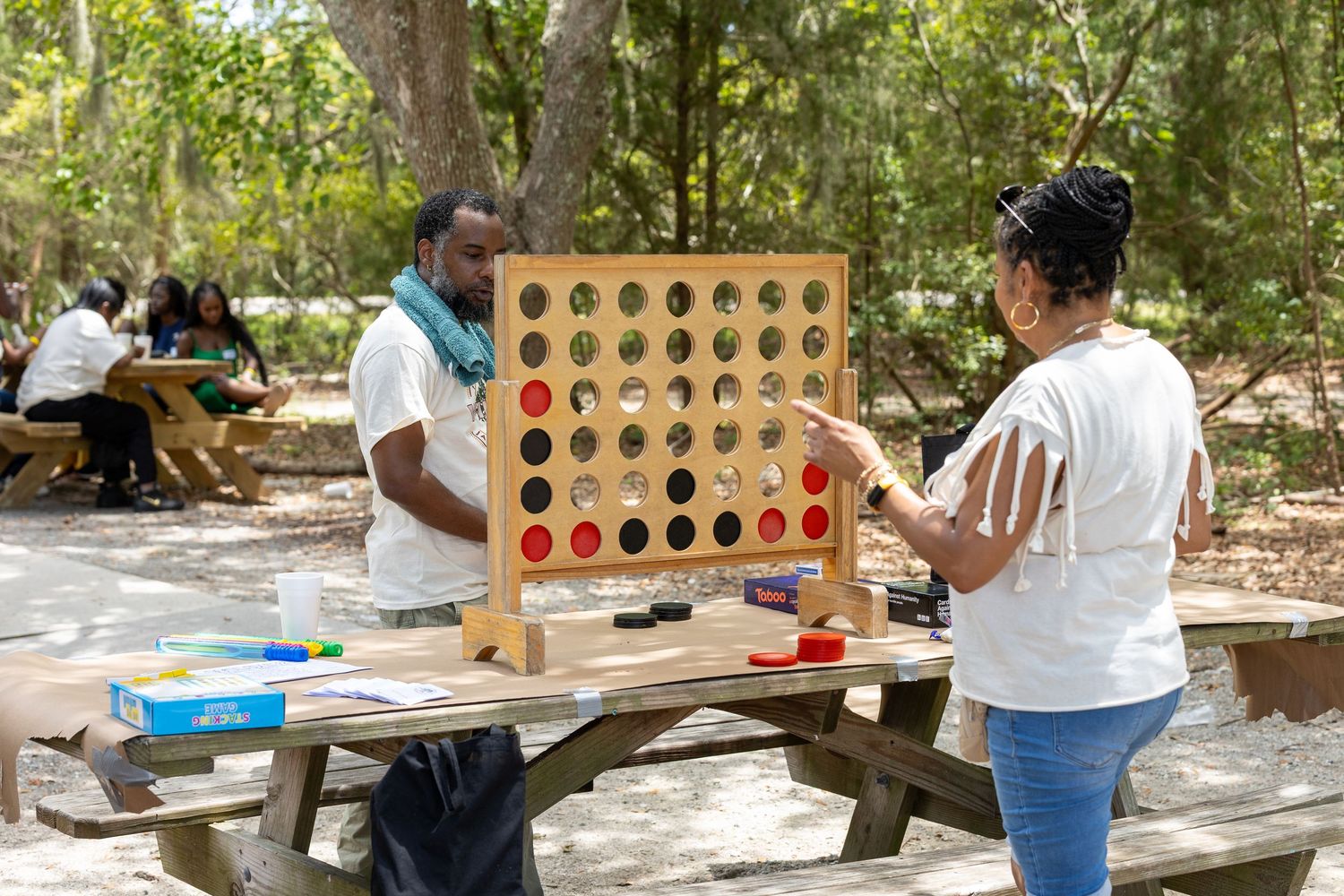 Two people playing a giant Connect Four game at an outdoor community event.