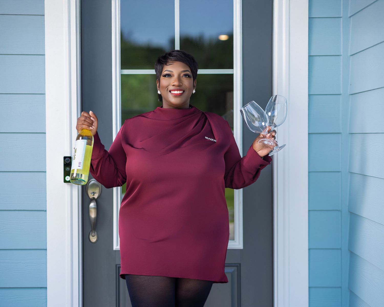 Real estate professional holding a bottle and wine glasses during a lifestyle branding session