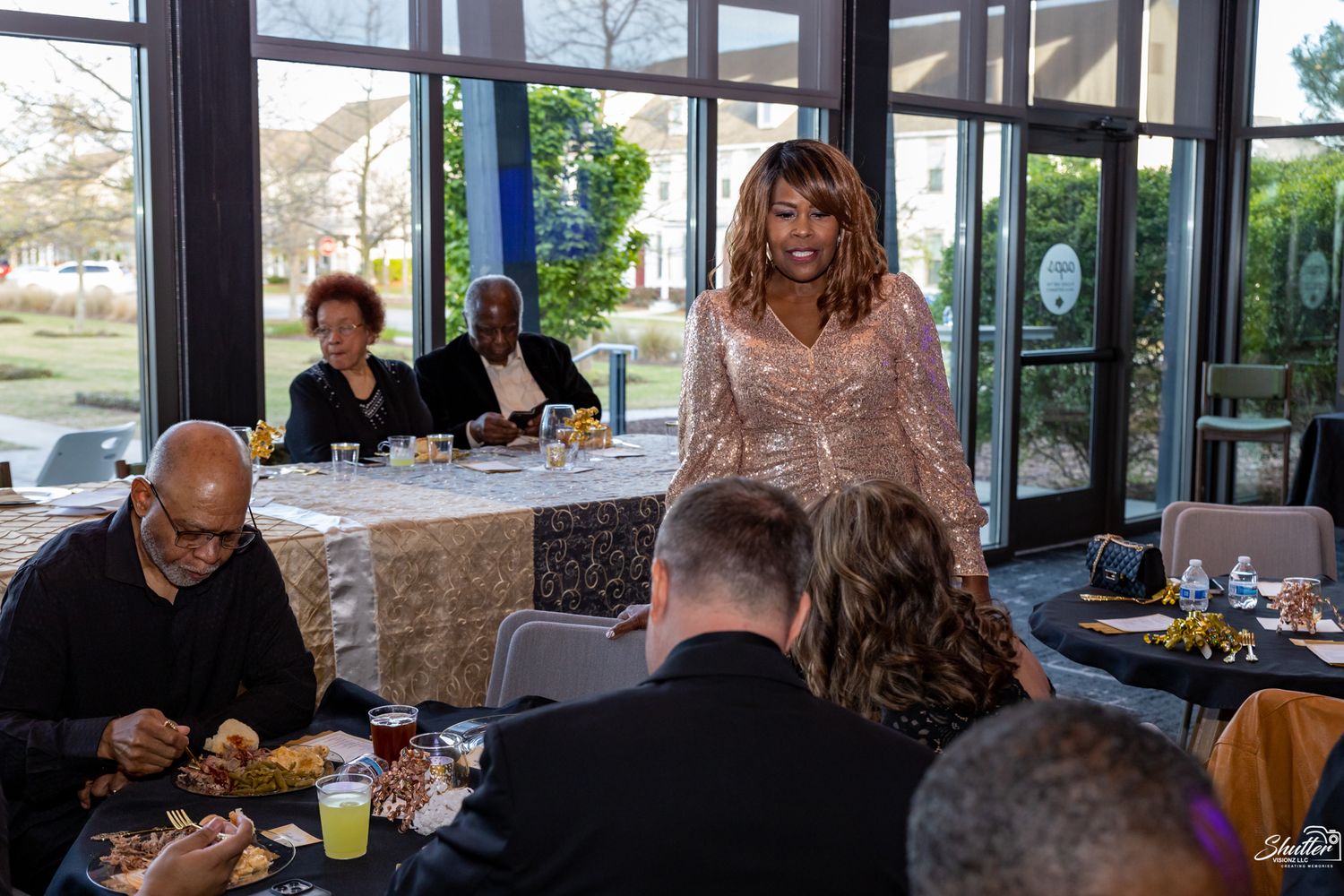 Woman in a sparkling dress walking through a room filled with guests during a celebration