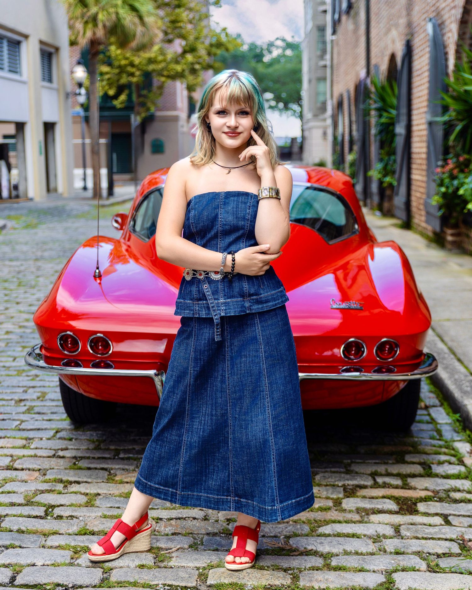 High school senior posing in front of a classic red Corvette on a historic street
