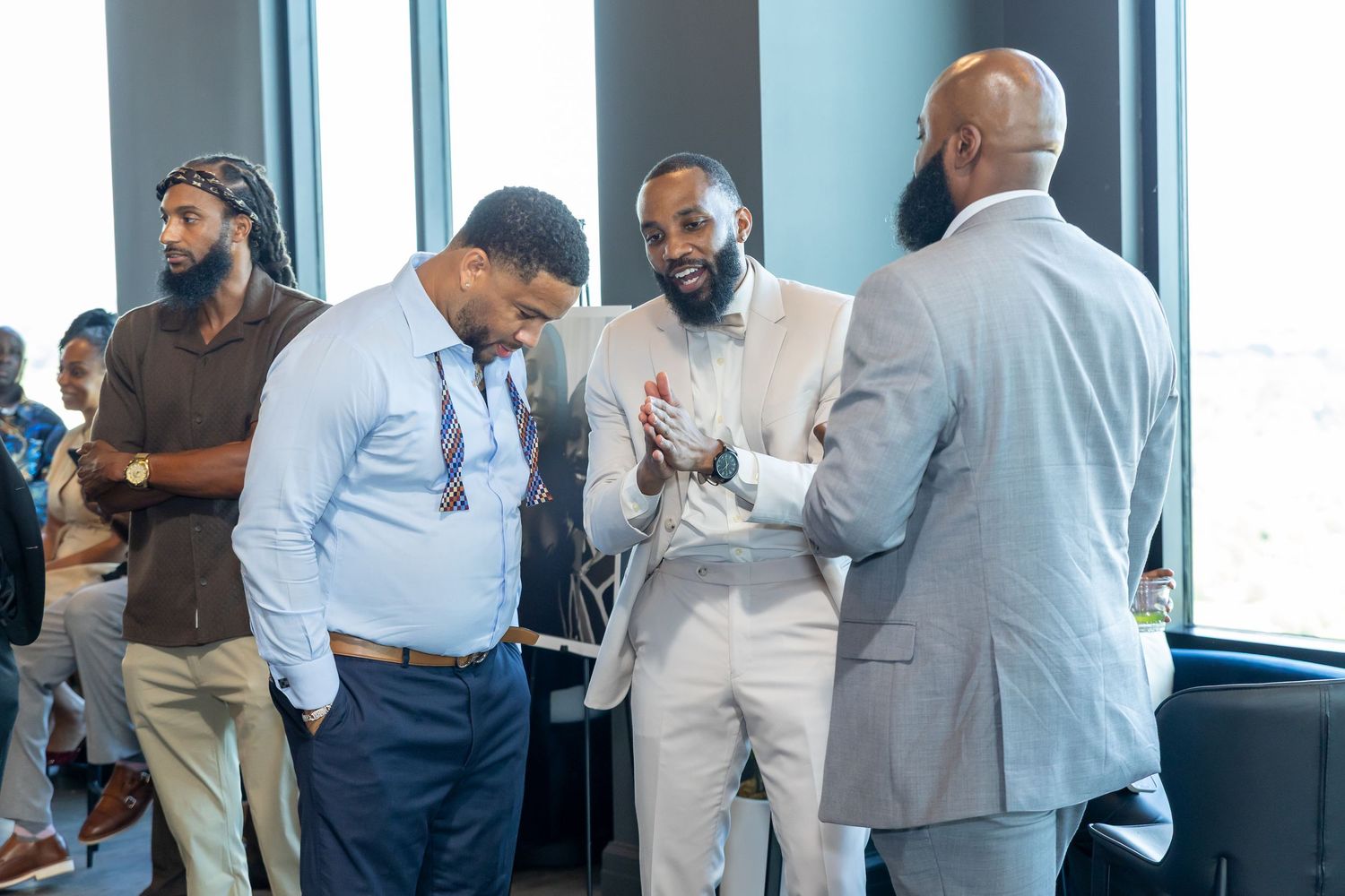 Well-dressed men in suits networking and conversing at a professional indoor event.