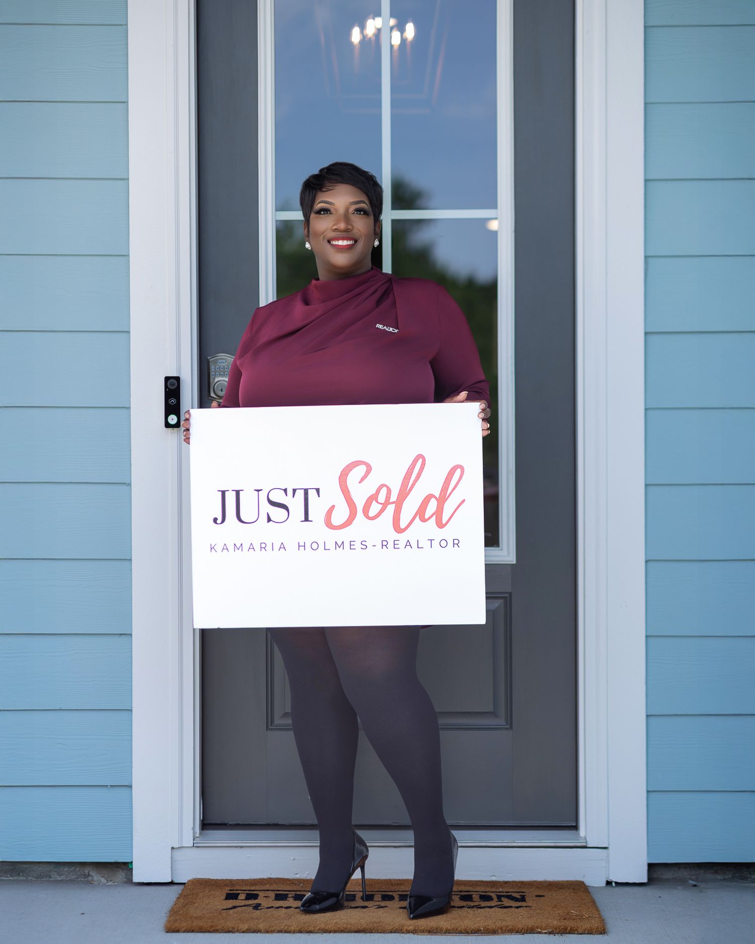 Real estate professional holding a “Just Sold” sign outside a home