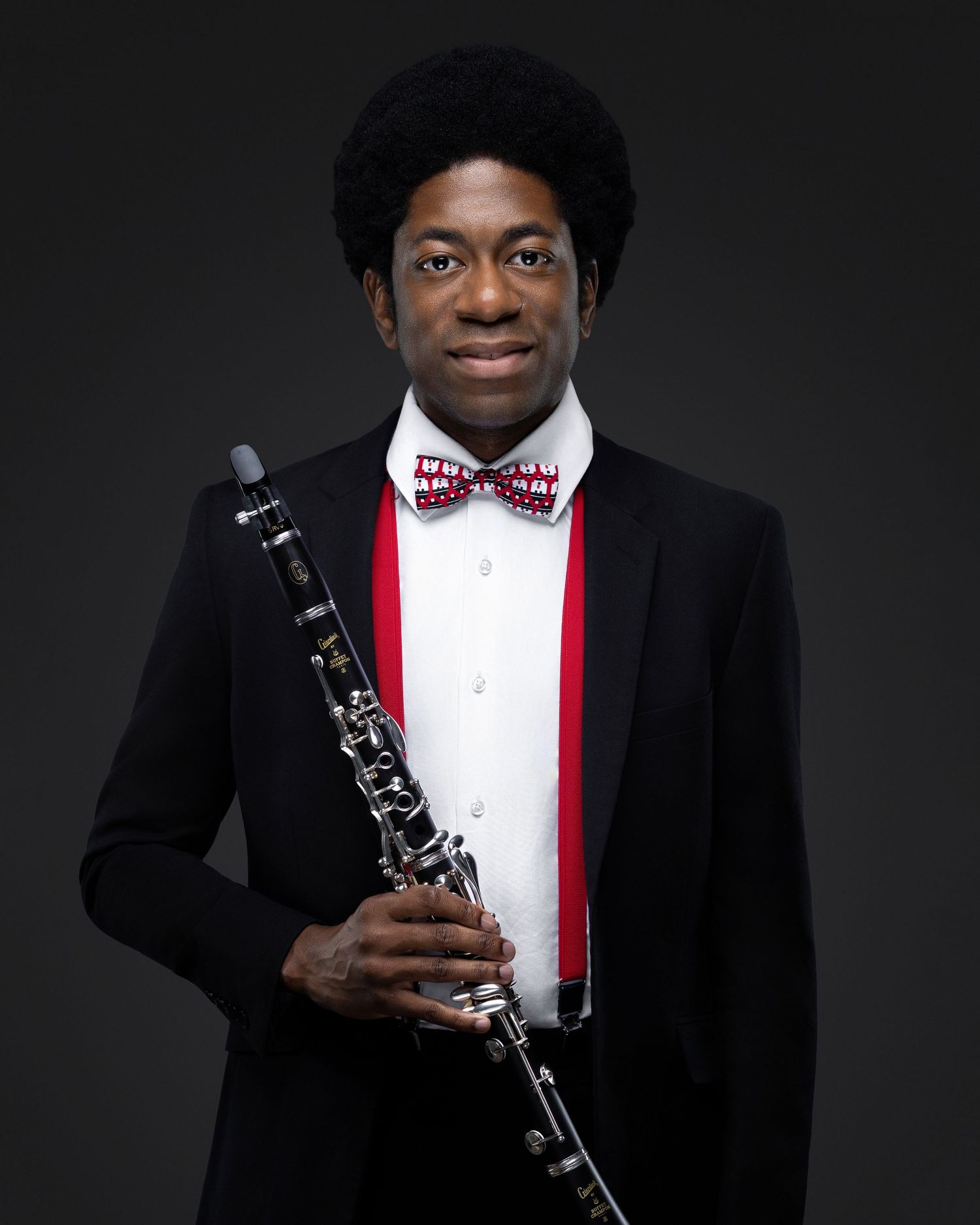 Musician in a black suit and patterned bow tie holding a clarinet