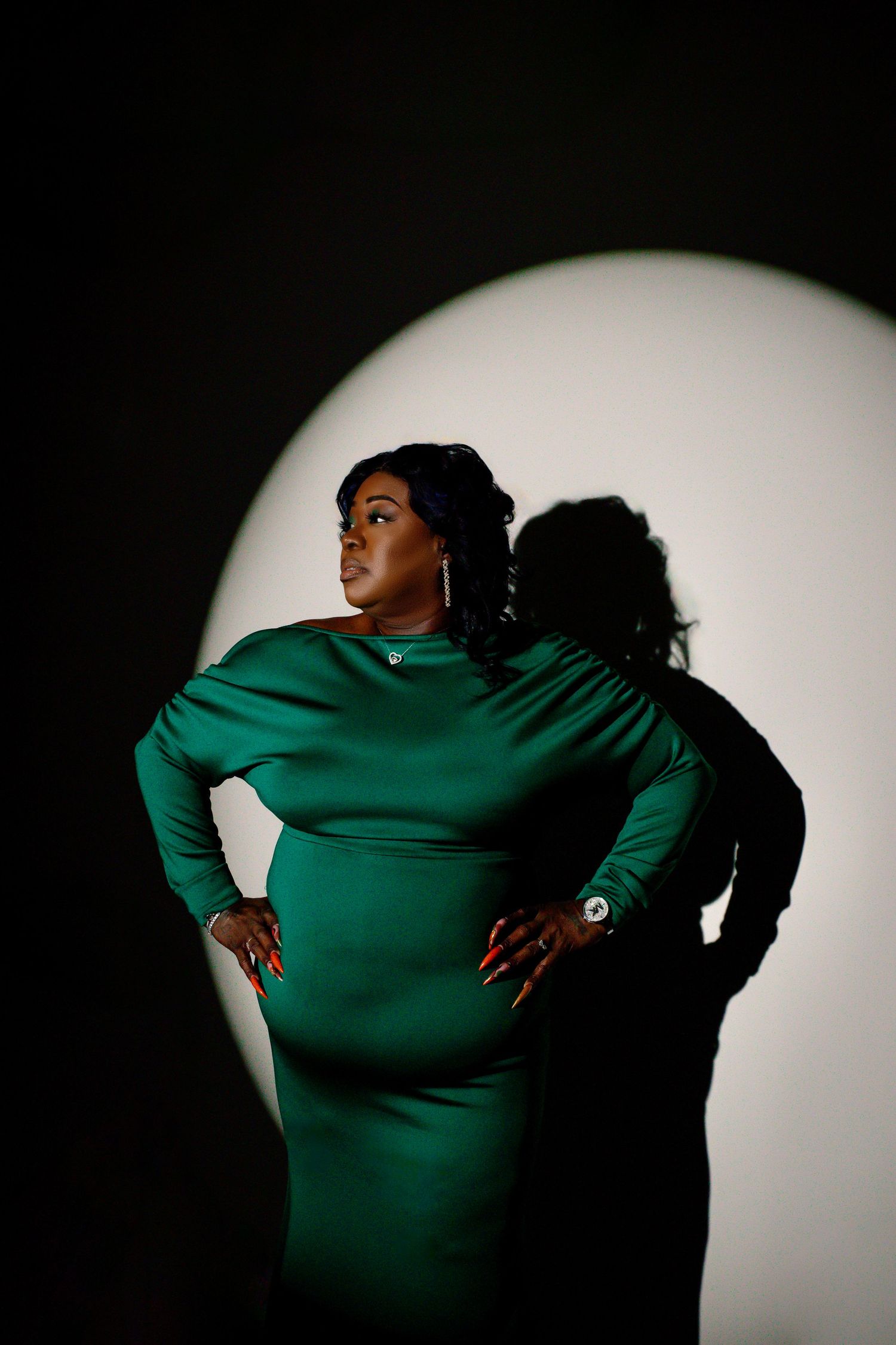 Woman posing in an elegant black gown under a dramatic spotlight