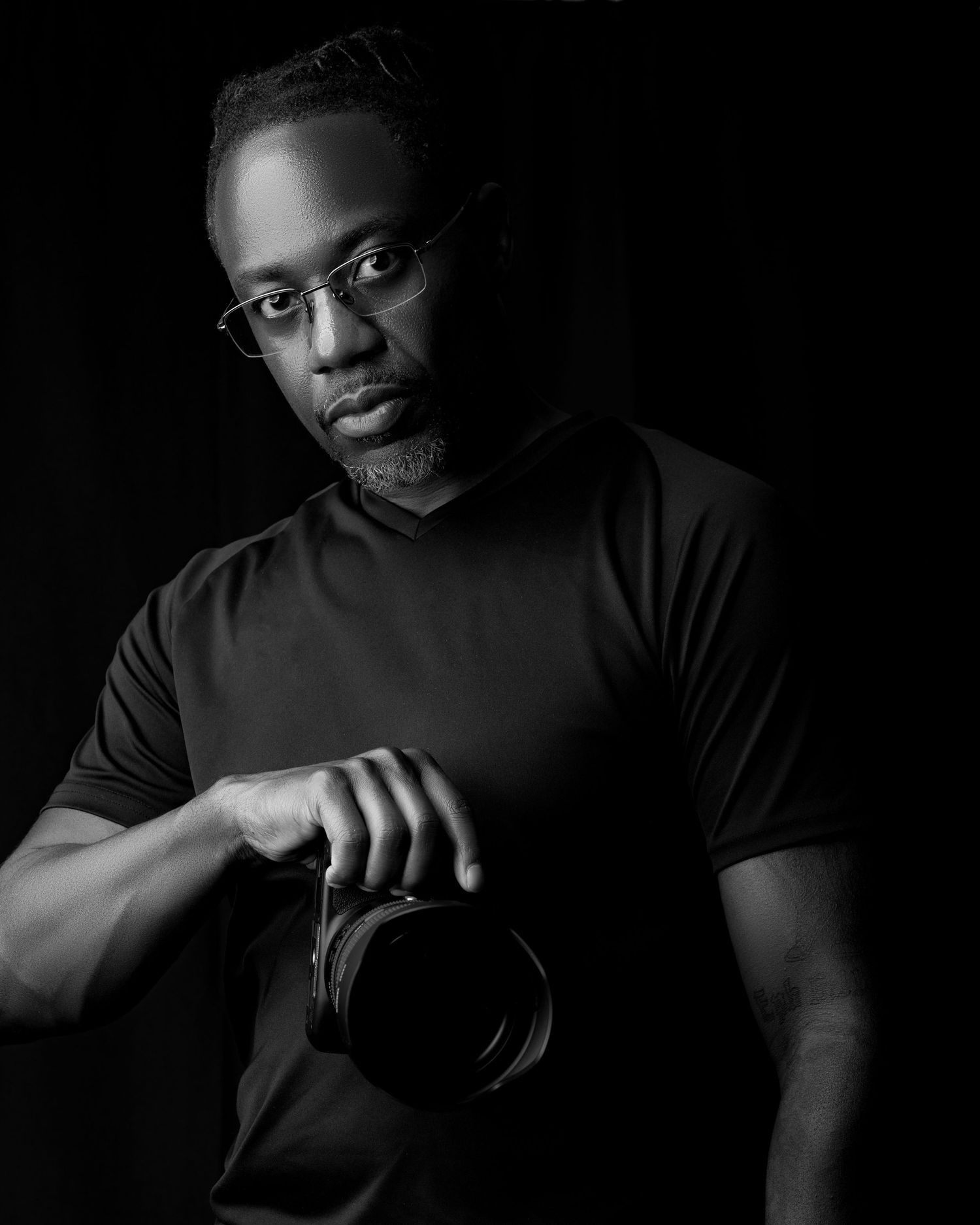 Black-and-white portrait of a photographer holding a professional camera