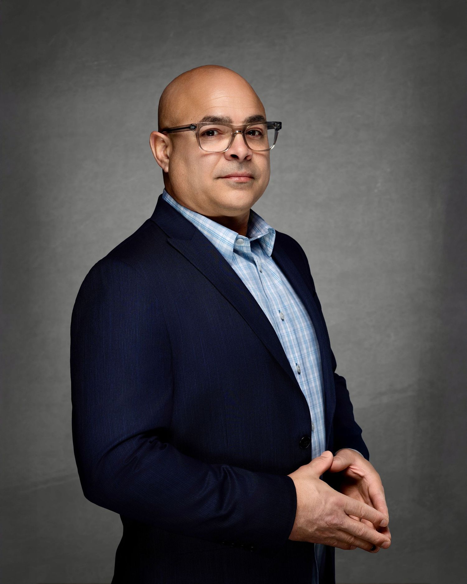Professional headshot of a man wearing glasses and a navy blazer