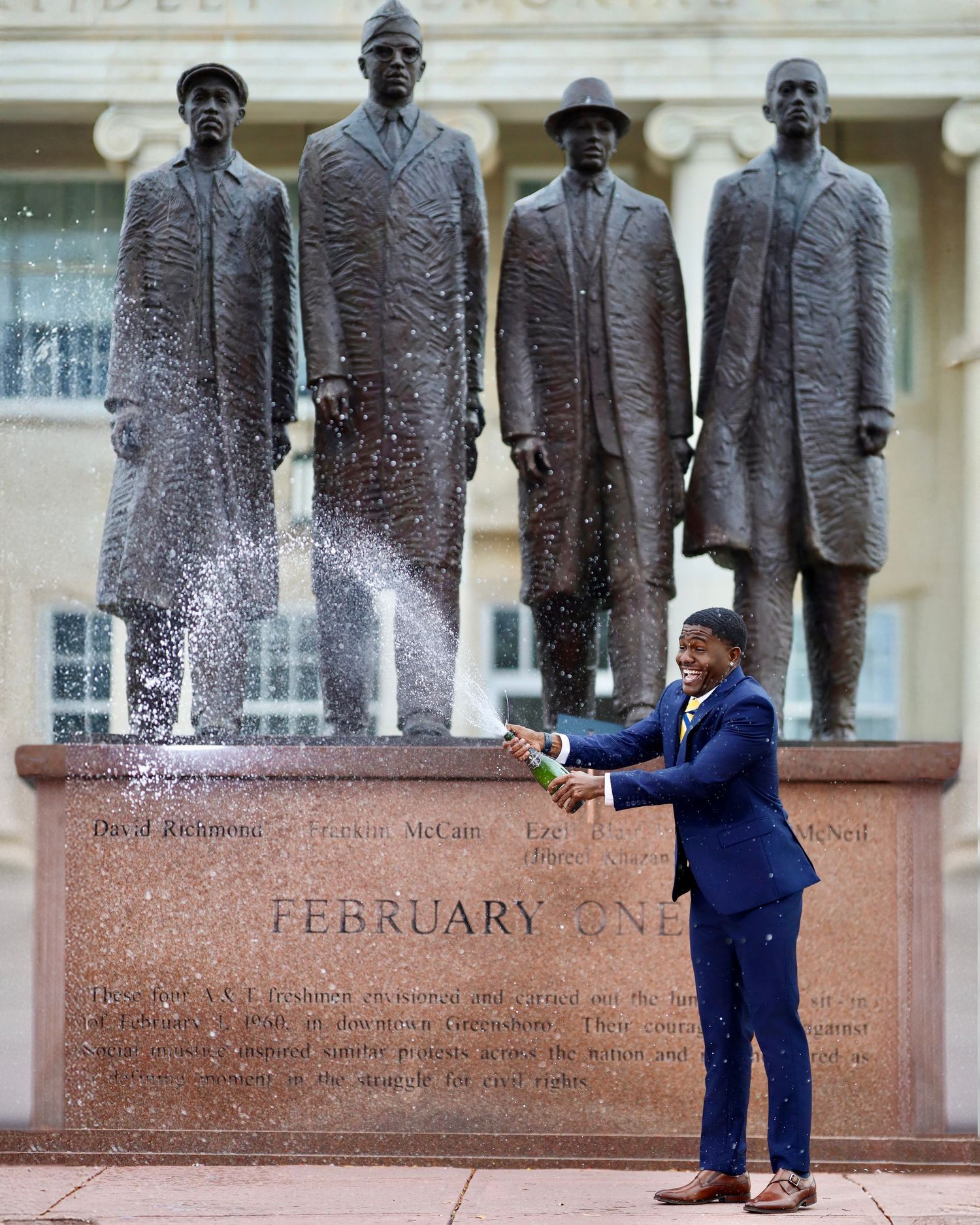 Graduate celebrating with a dramatic champagne spray during a professional graduation photography session