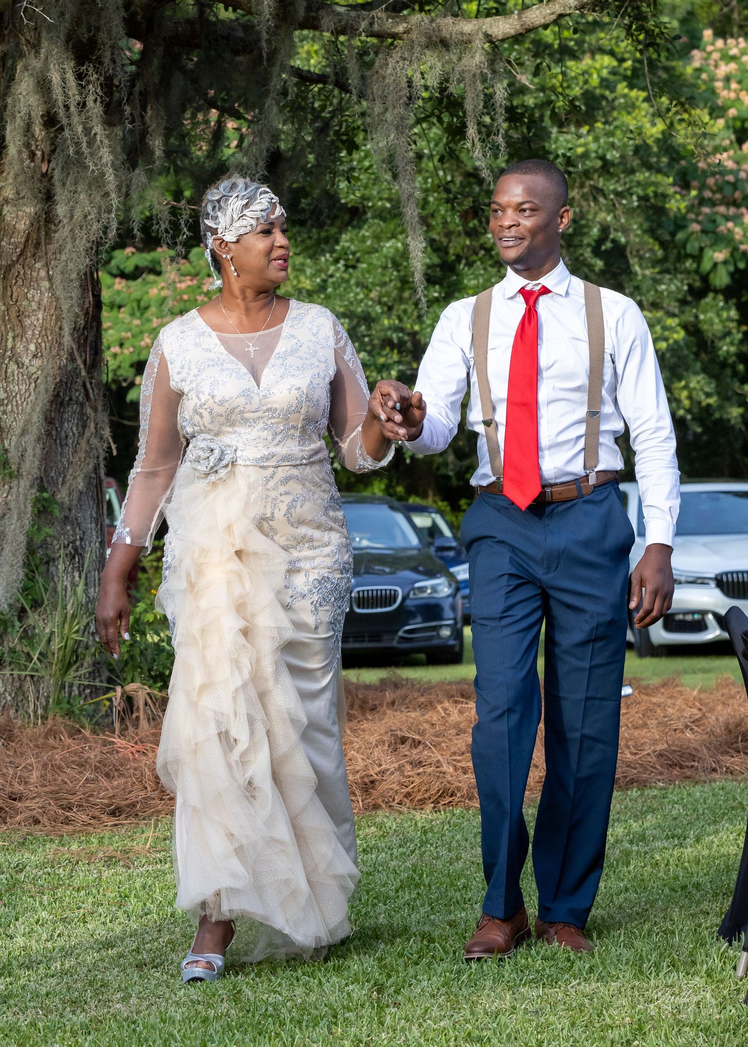 Elegantly dressed woman walking outdoors beside a man wearing a red tie
