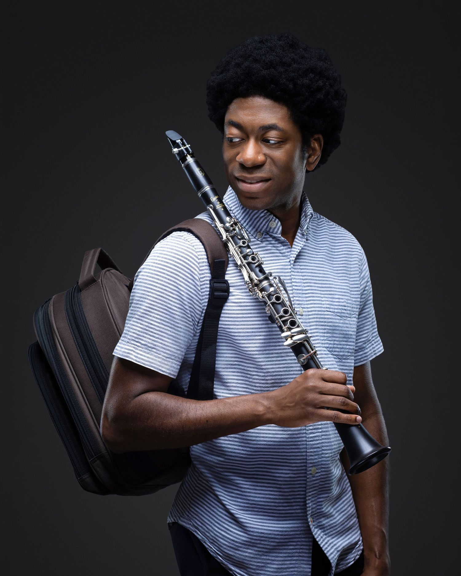 Musician holding a clarinet and carrying an instrument case during a professional portrait session