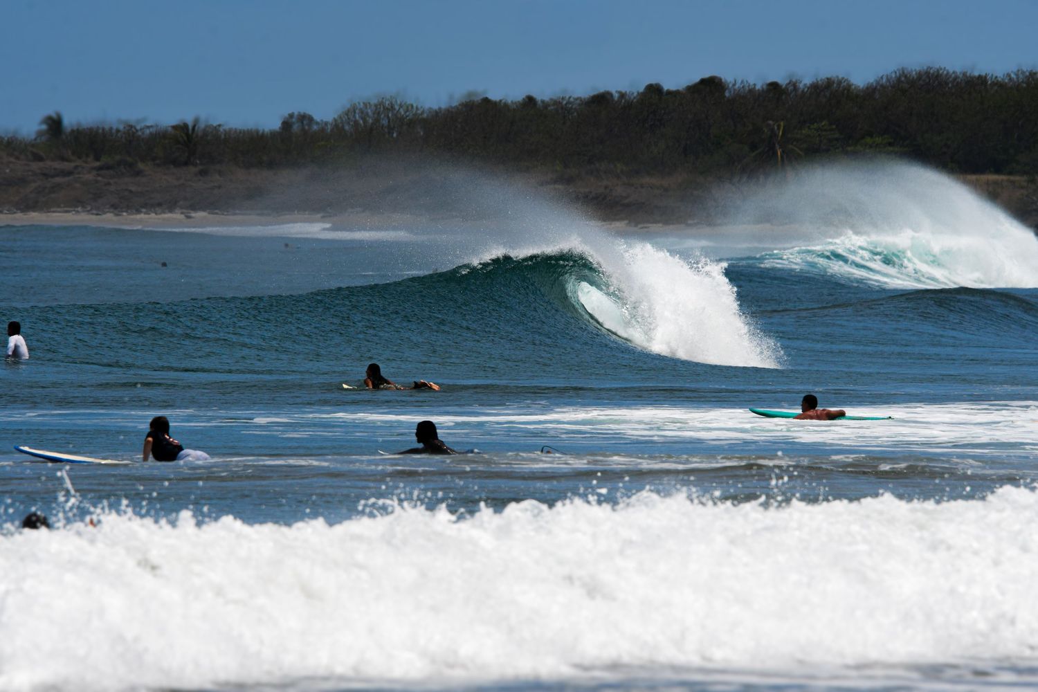Surfers riding a wave at Playa Avellanas, Costa Rica
