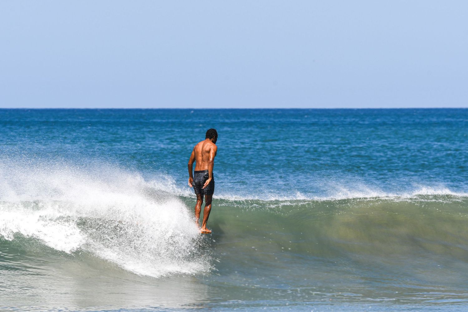 Surfer riding a wave at Playa Avellanas, Costa Rica