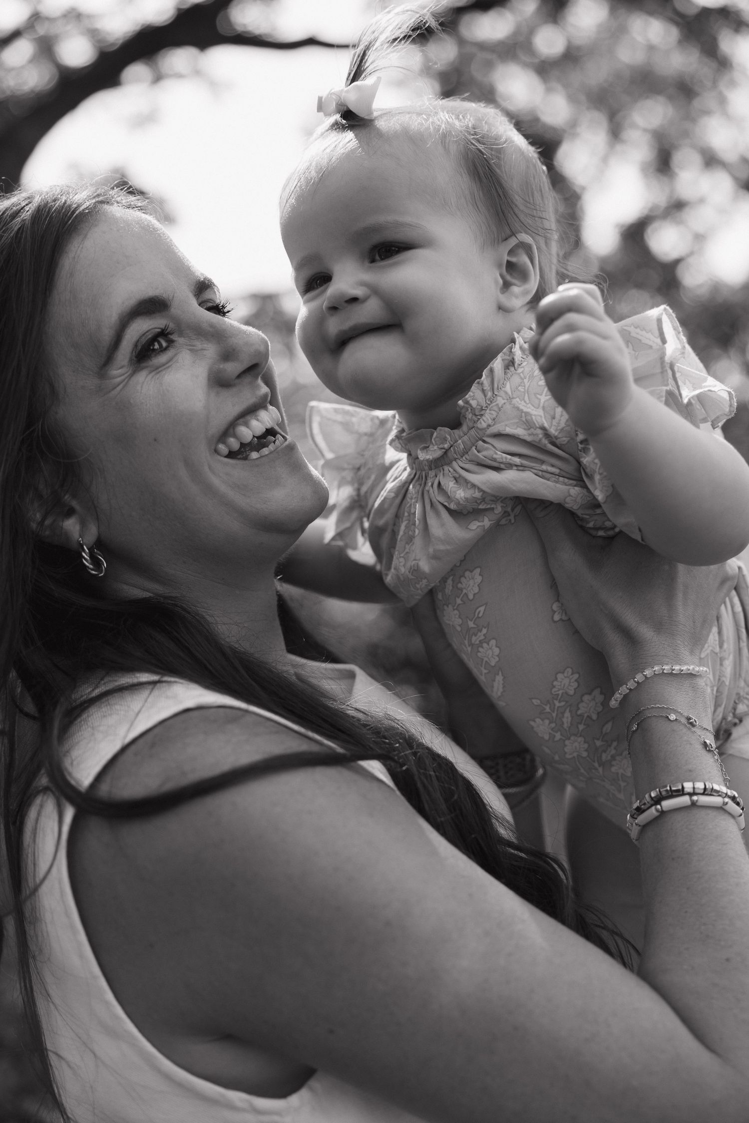 Black and white portrait of a laughing mother holding her smiling baby girl.