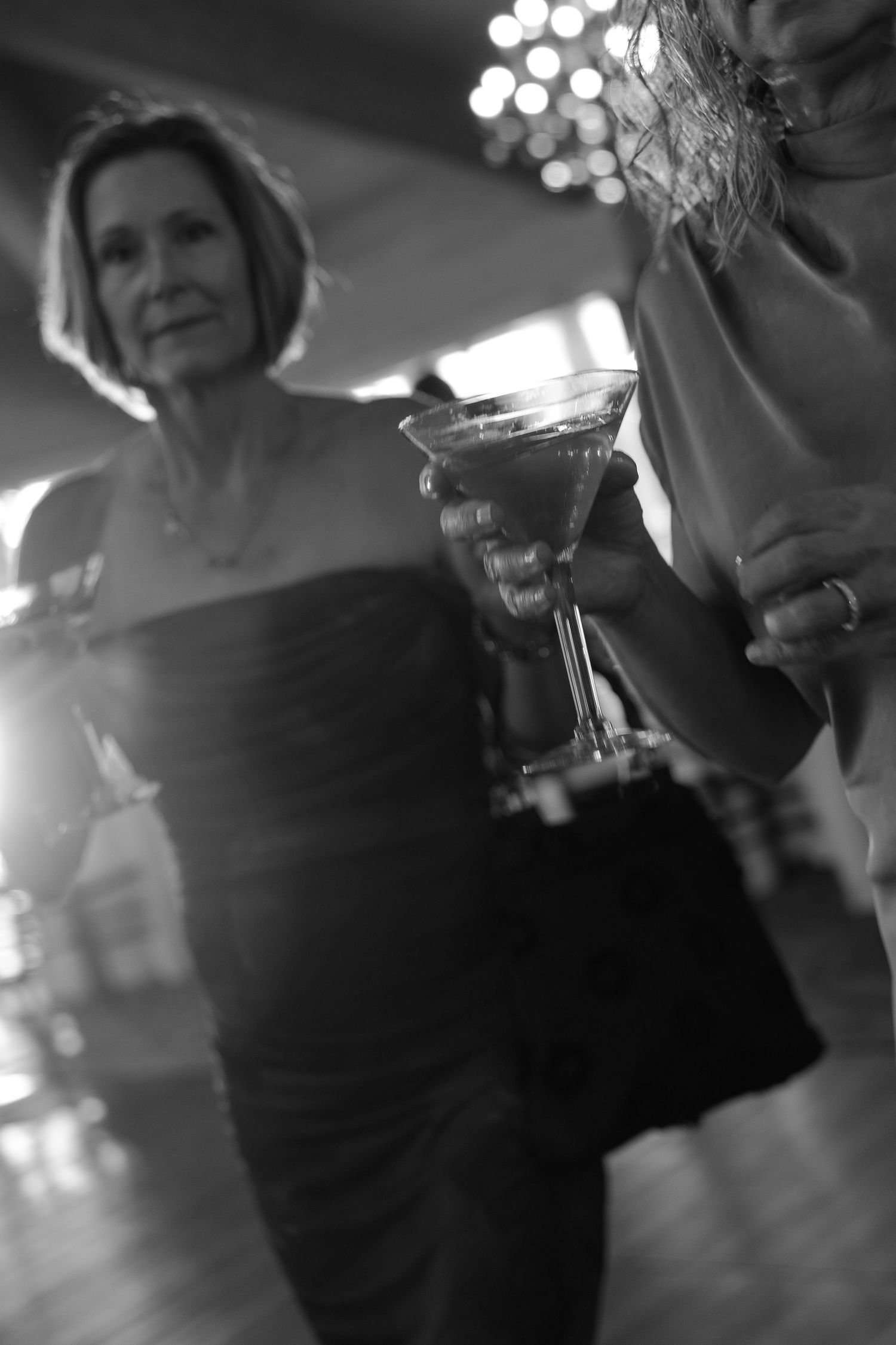 Black and white photo of elegant women holding martini glasses at a formal evening event.