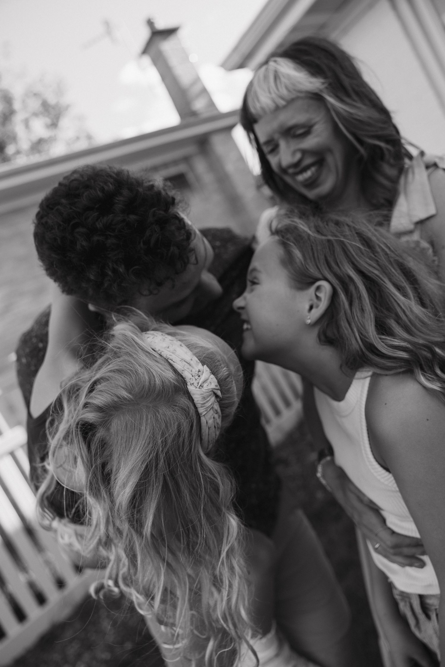 Black and white candid photo of group of laughing women and girls gathered closely together outdoors.