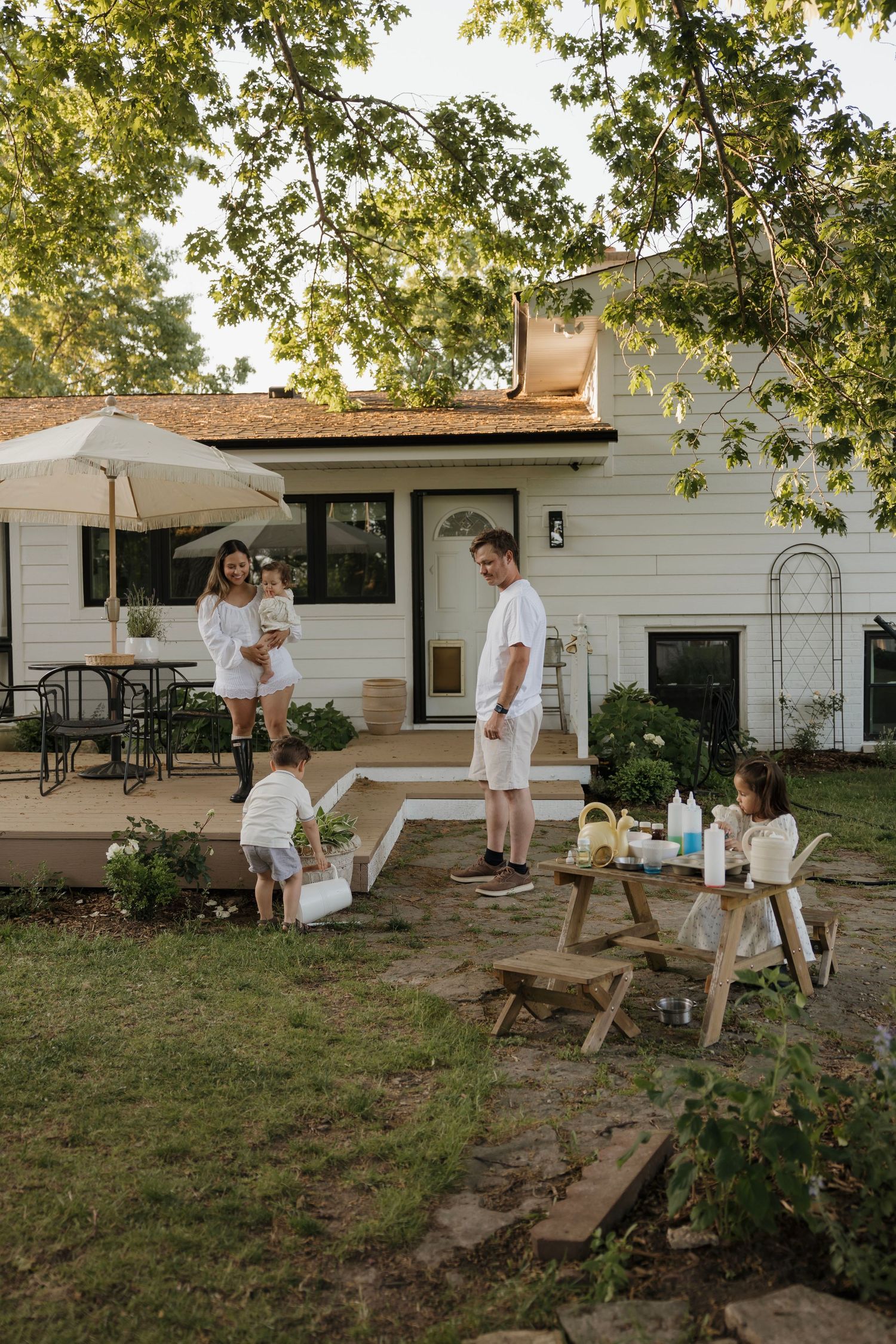 Family in white outfits enjoying a sunny afternoon in their charming backyard garden.