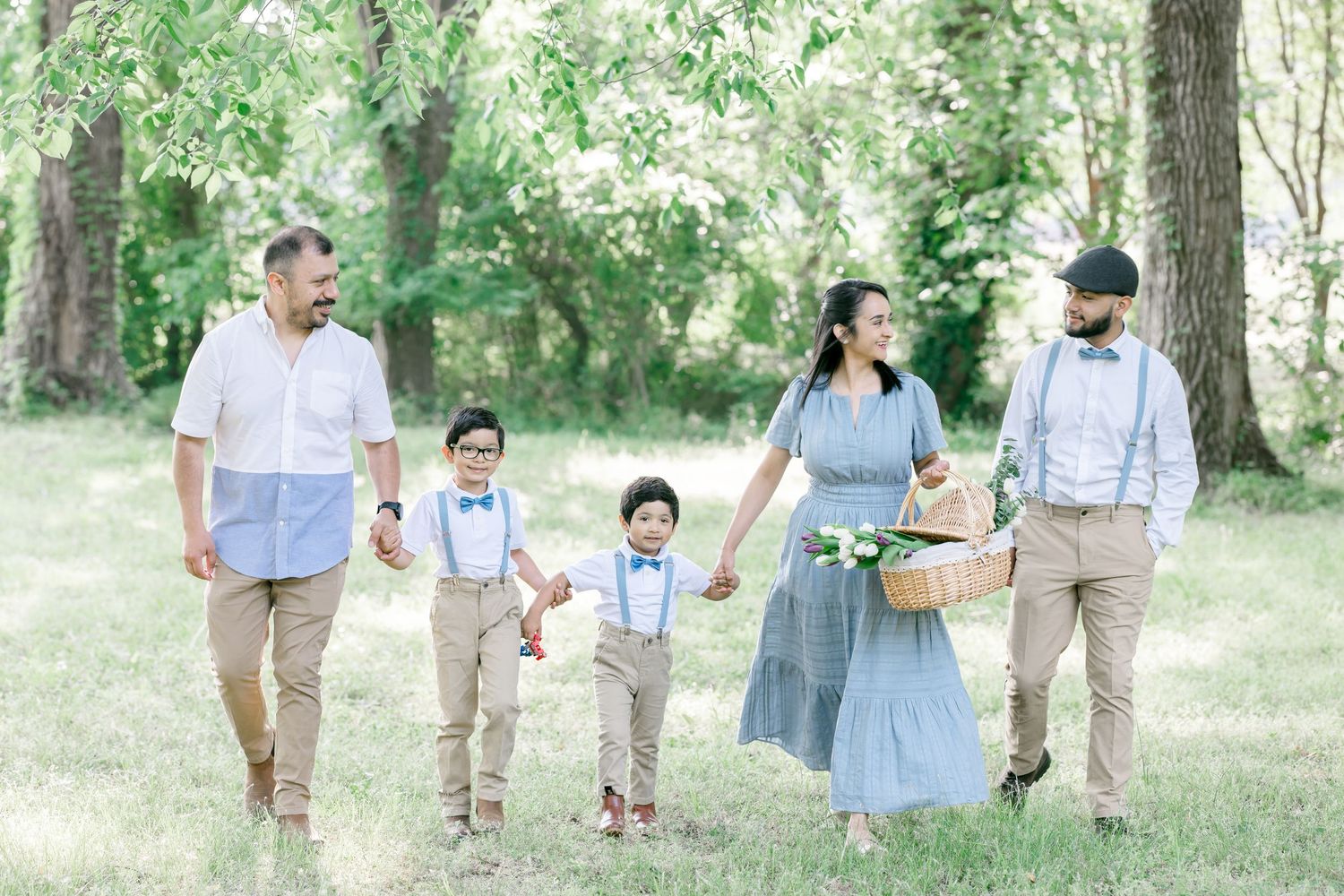Family of five walking in a sunny park, dressed in coordinating blue and tan outfits, carrying a picnic basket.