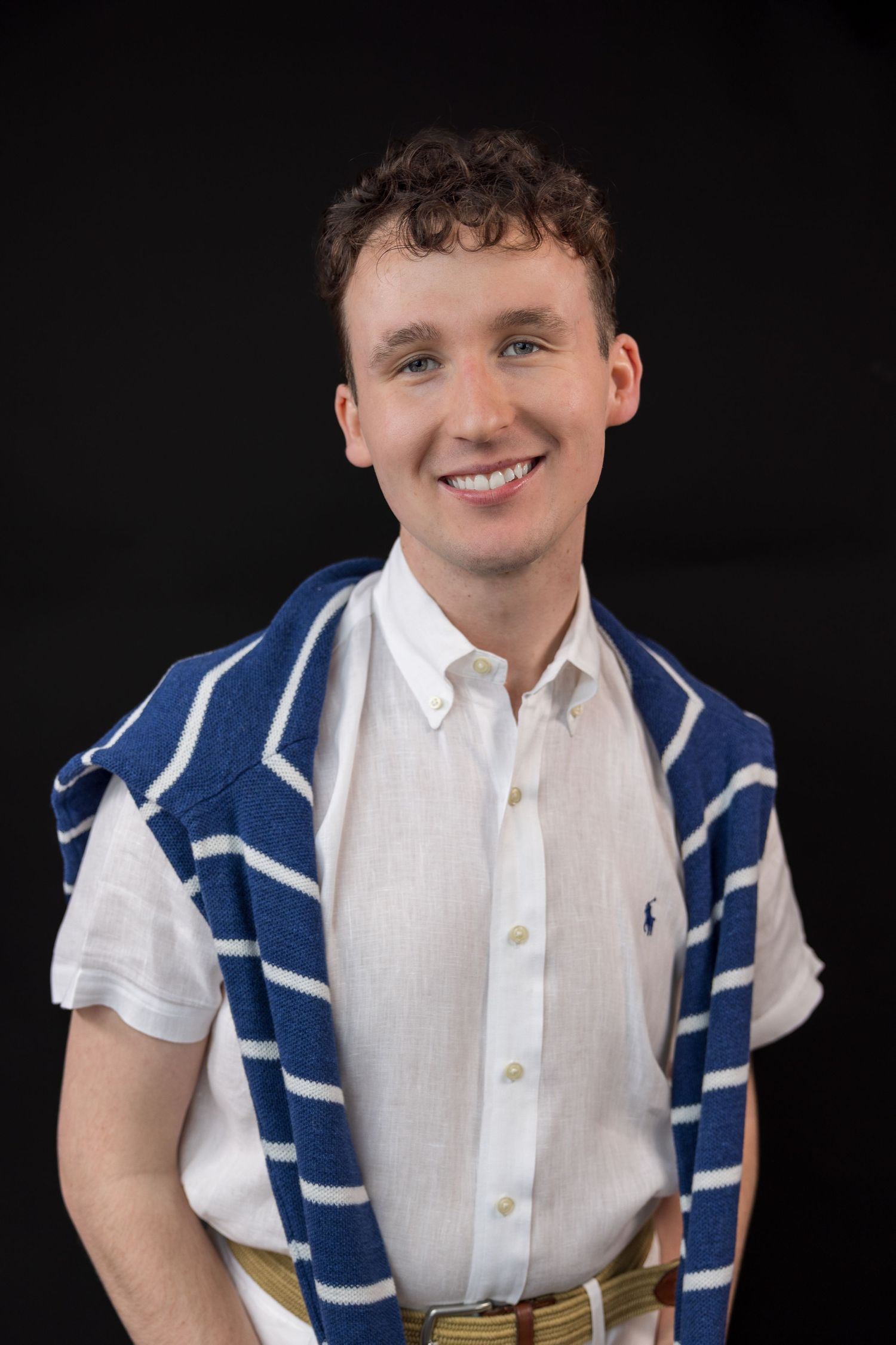 Person wearing white shirt and blue striped scarf against dark backdrop.