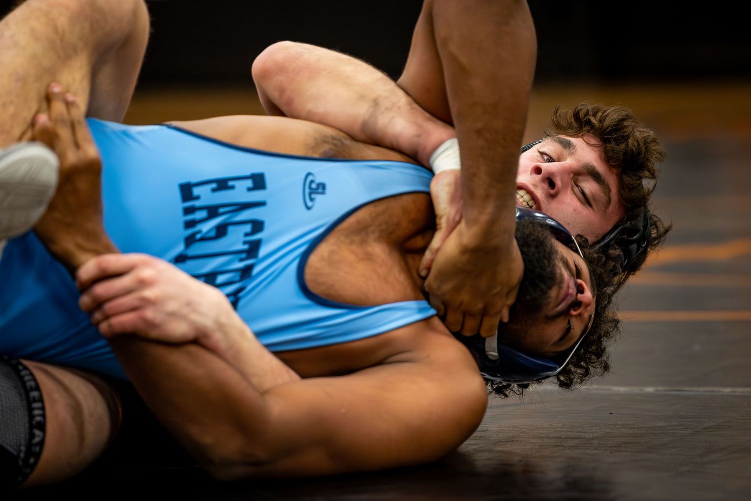 Wrestlers in blue and black uniforms competing during a match on the mat. Studio portrait of a youth athlete. Team photos.