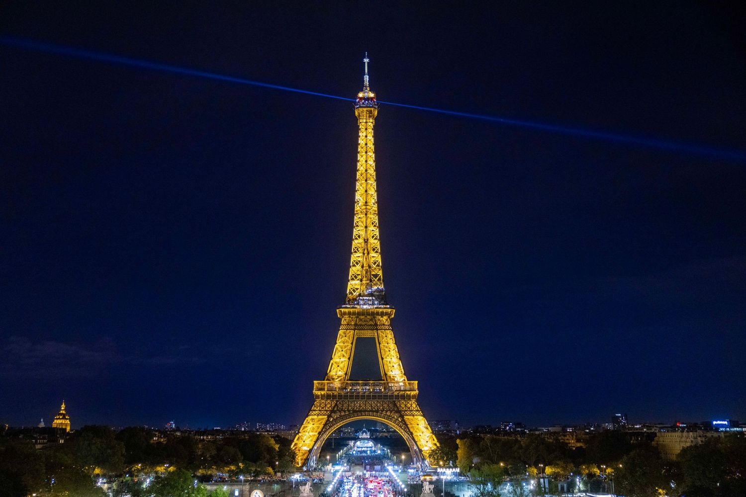 Illuminated Eiffel Tower glowing golden against the night sky in Paris.