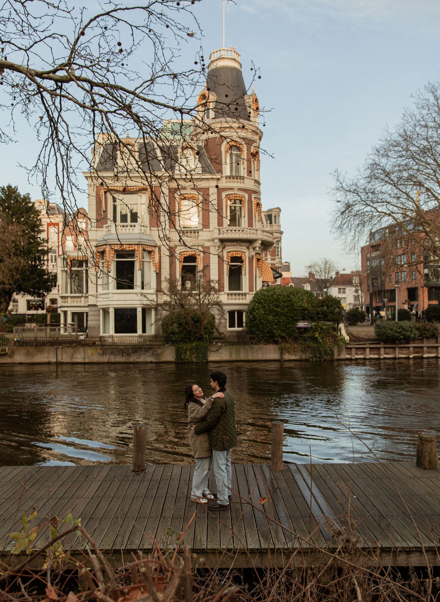 Beautiful historic building with ornate architecture reflects in waterfront during sunset.