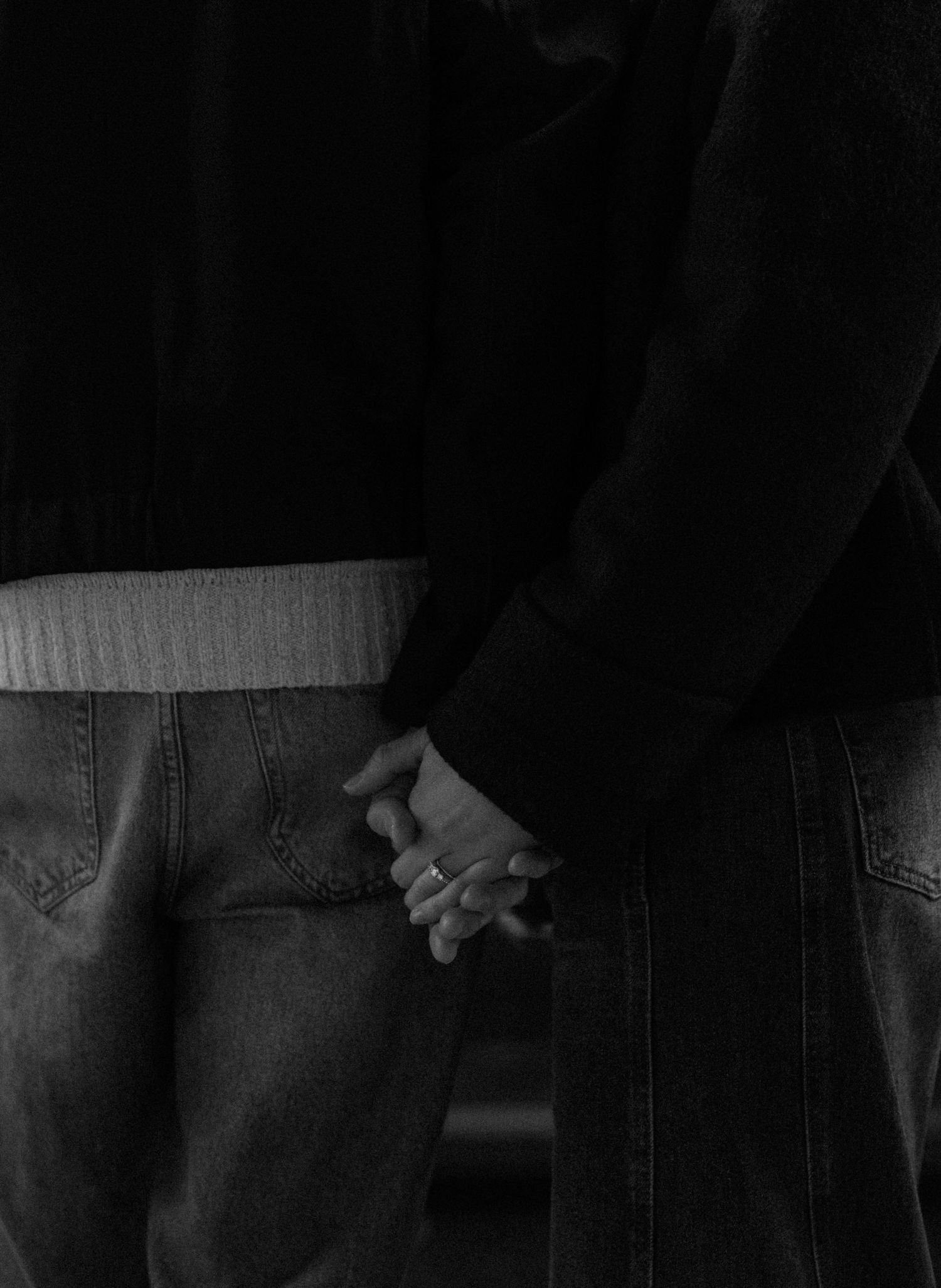Black and white close-up image of two people holding hands in a tender moment.