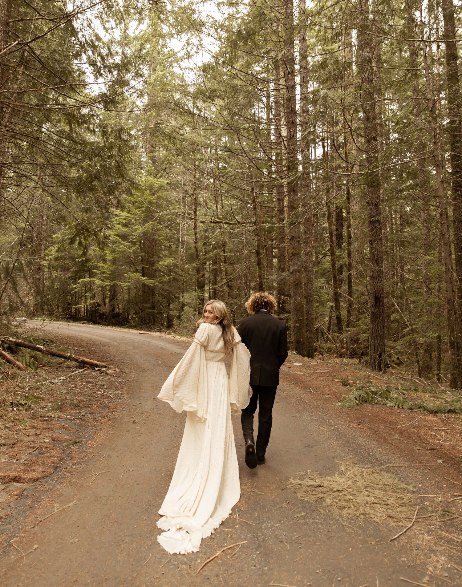 Artistic wedding portraits taken on a winding forest path in warm natural light.