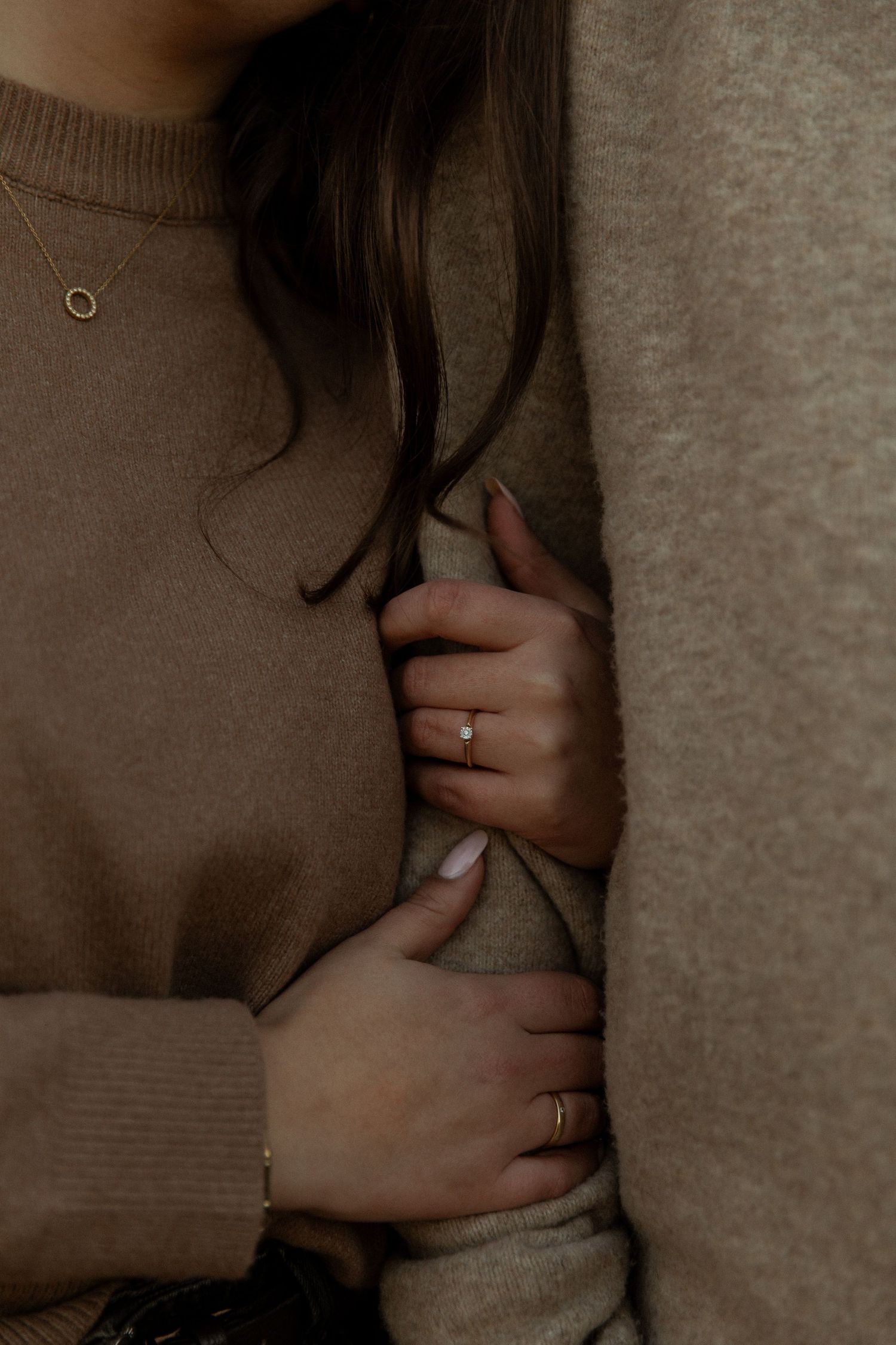 Hands delicately touching a soft gray sweater in warm lighting.