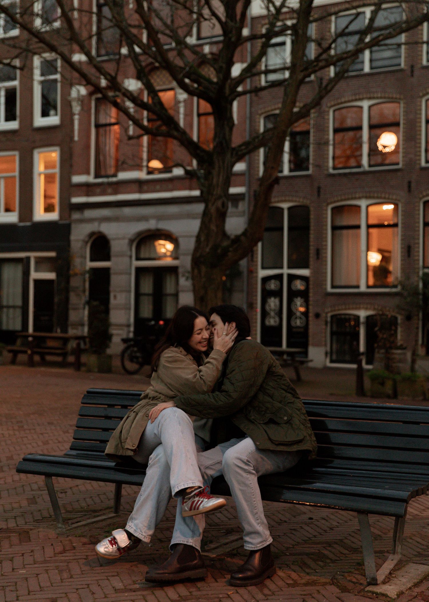 Couple sharing a tender moment on a park bench at dusk.
