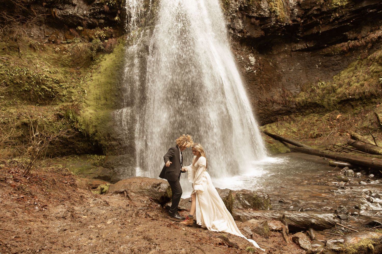 Dreamy waterfall scene with couple sharing intimate moment in forest setting.