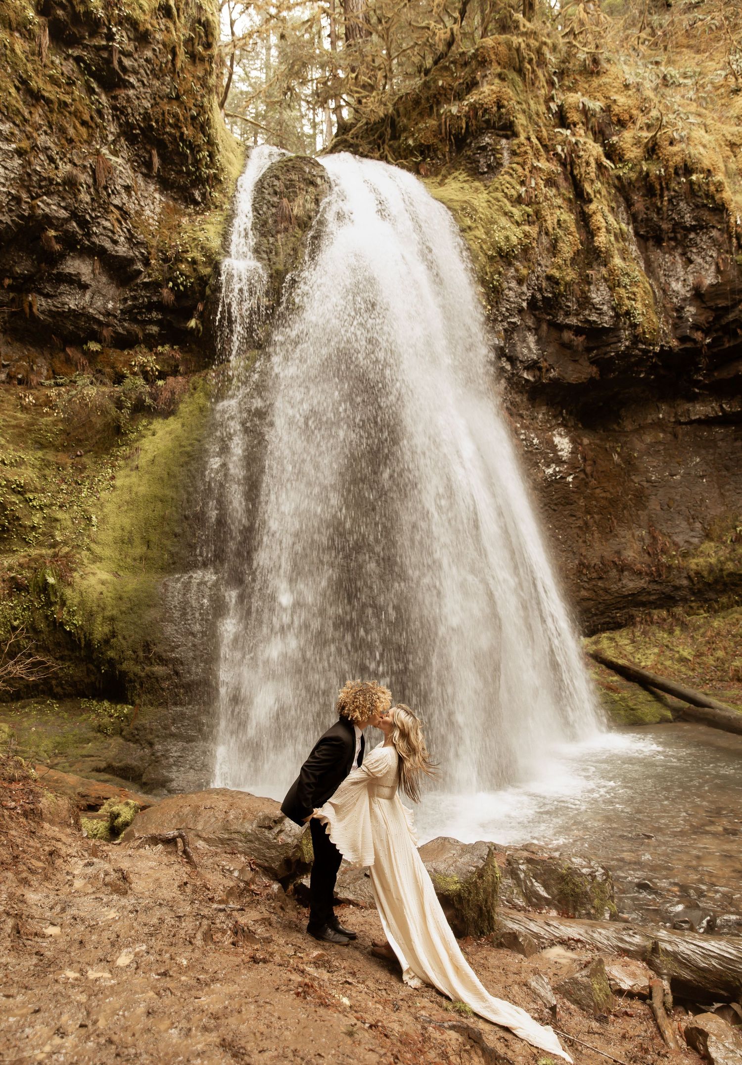 A scenic waterfall creates a dramatic backdrop for a romantic photoshoot in nature.