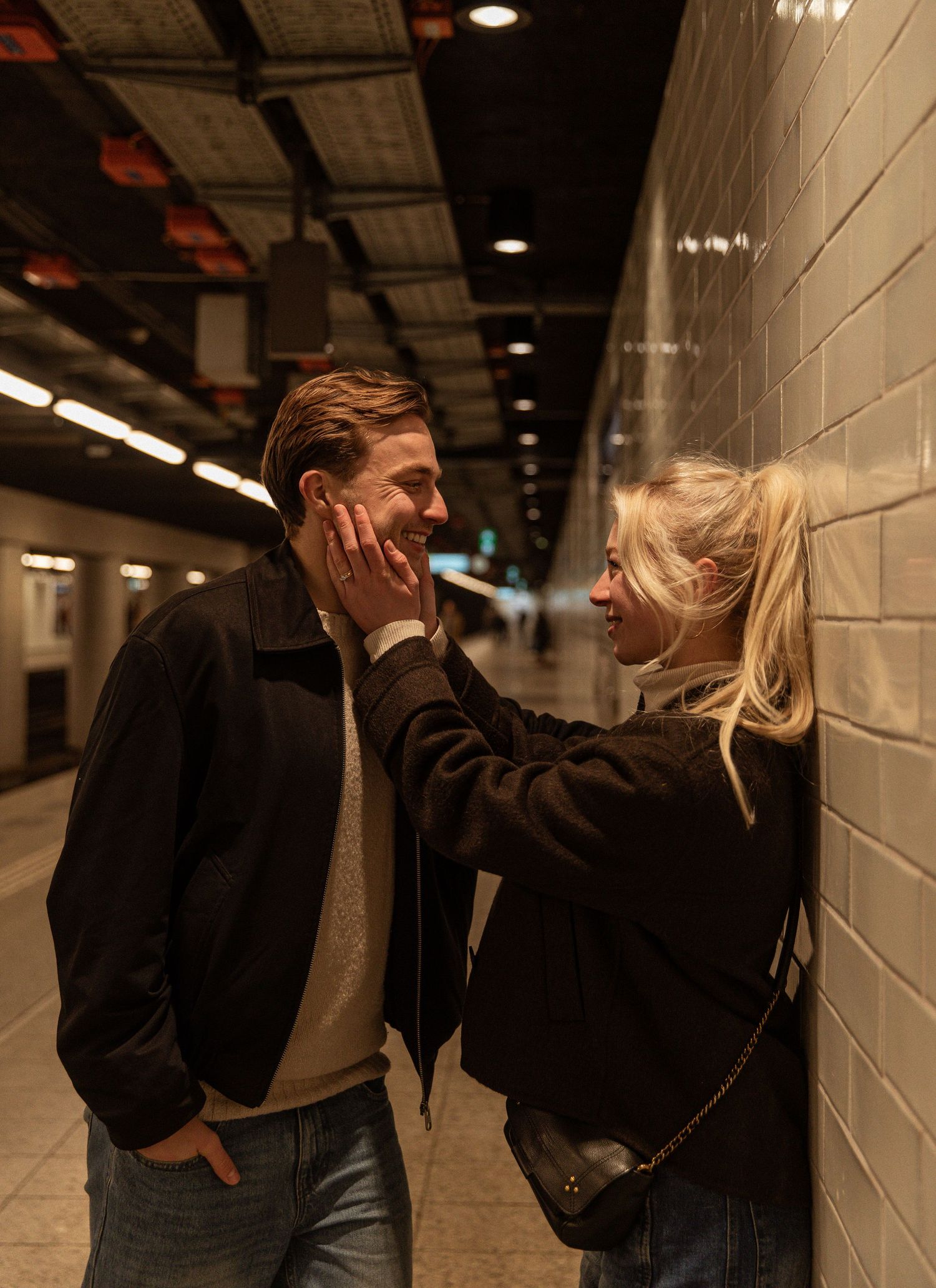 A sequence of five dramatic photos showing a couple dancing and embracing in a dimly lit subway tunnel corridor.