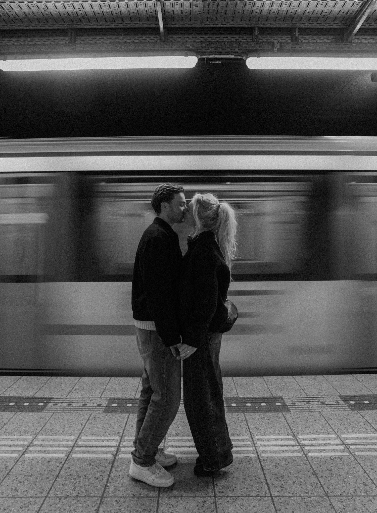 A series of black and white photos showing silhouettes of people waiting on a subway platform as trains blur past in motion.
