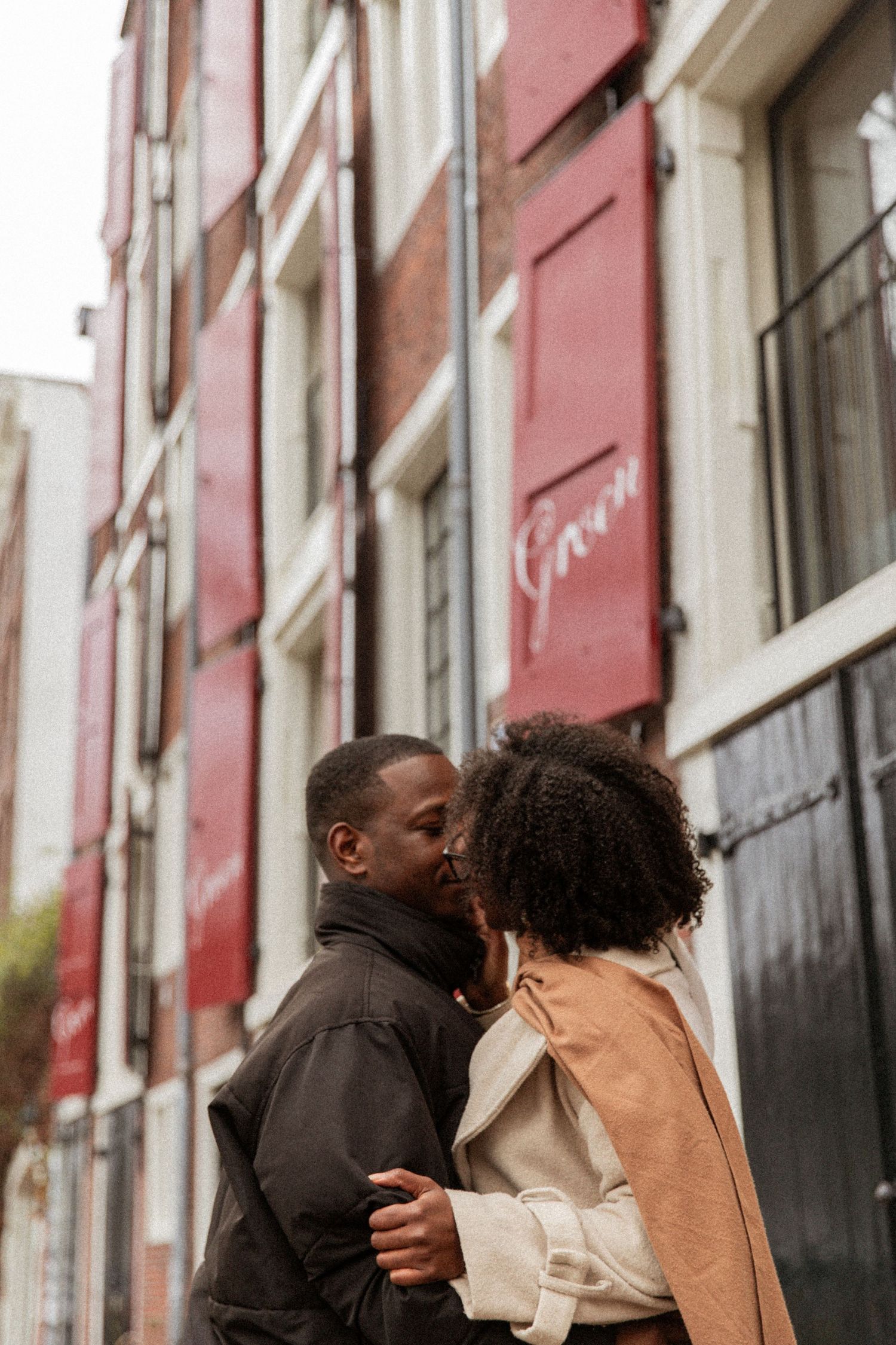 A romantic couple sharing an intimate moment on a city street with pink buildings.
