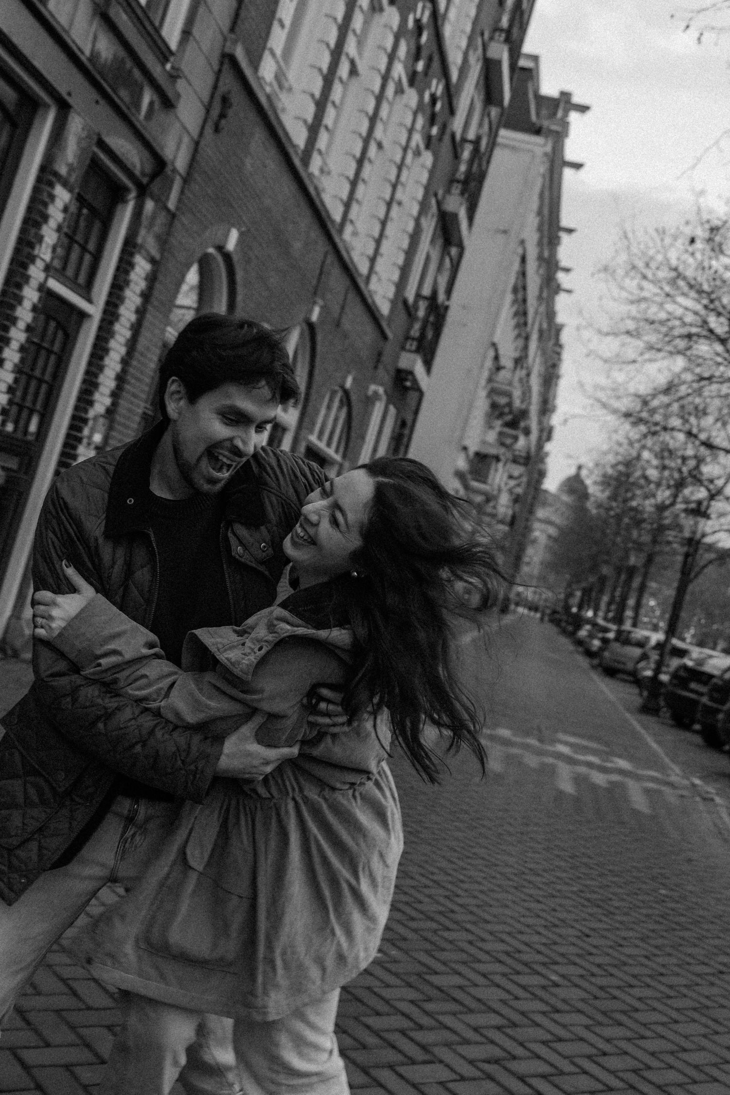 Couple sharing an intimate moment on a cobblestone street in the city.