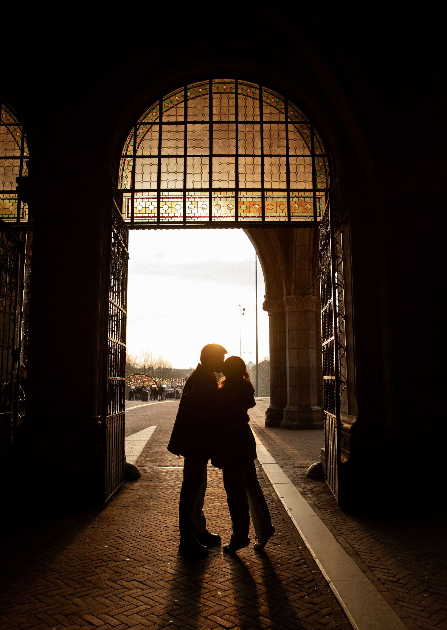 Silhouette of a couple embracing in an arched doorway at sunset.