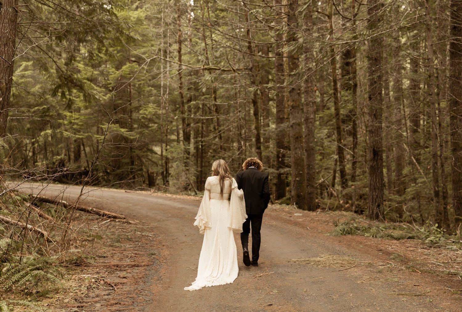 Wedding photography session on a peaceful forest trail surrounded by tall evergreen trees.