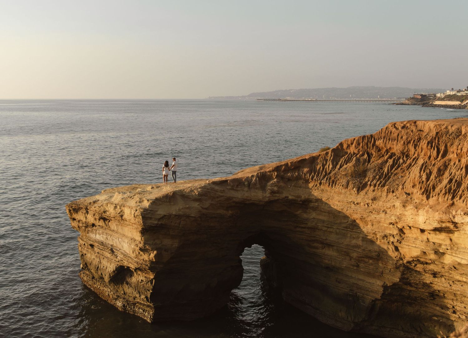 Scenic coastal landscape showing rocky cliffs and ocean waves at sunset.