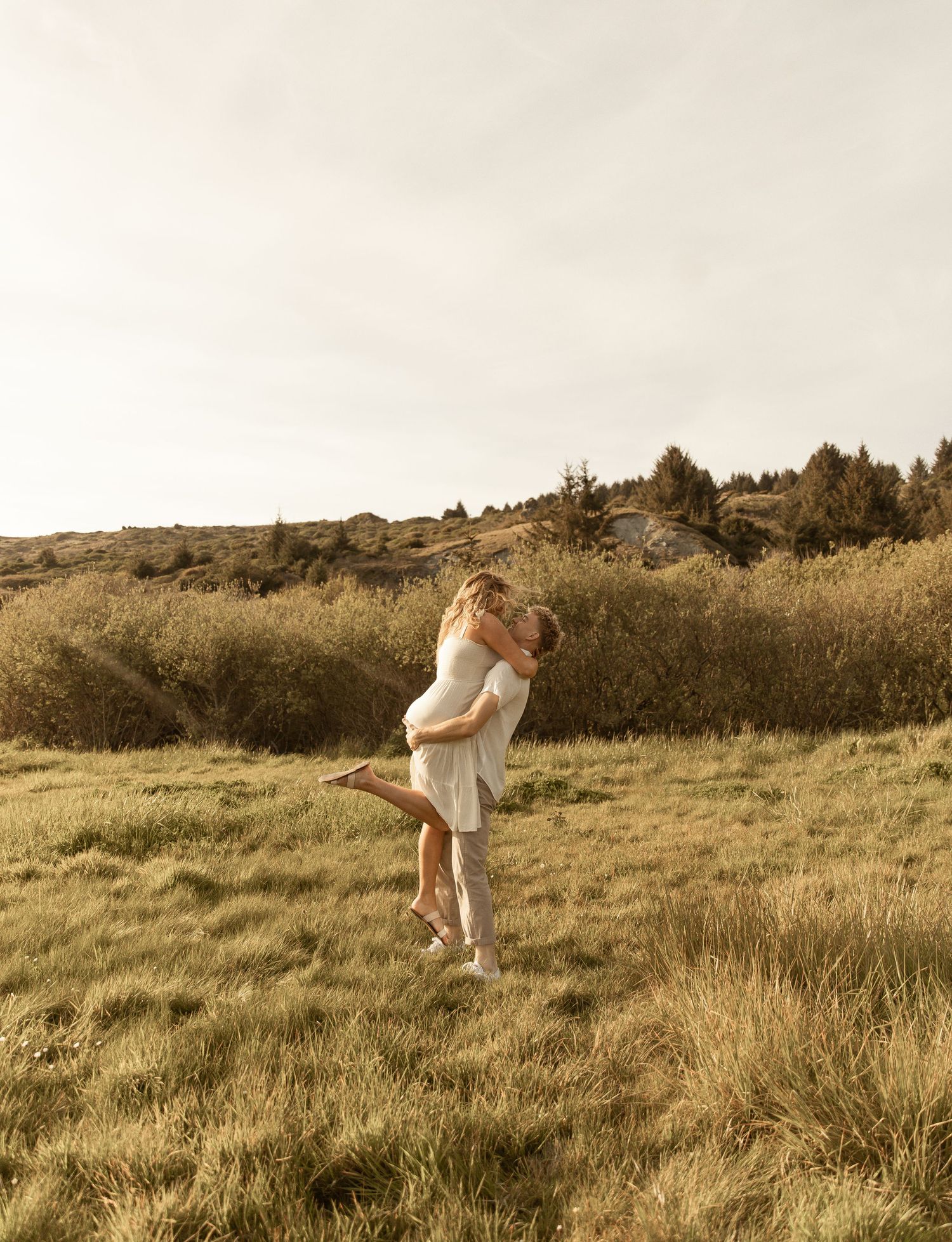 A couple embraces in a romantic sequence of photos taken in a golden field at sunset.