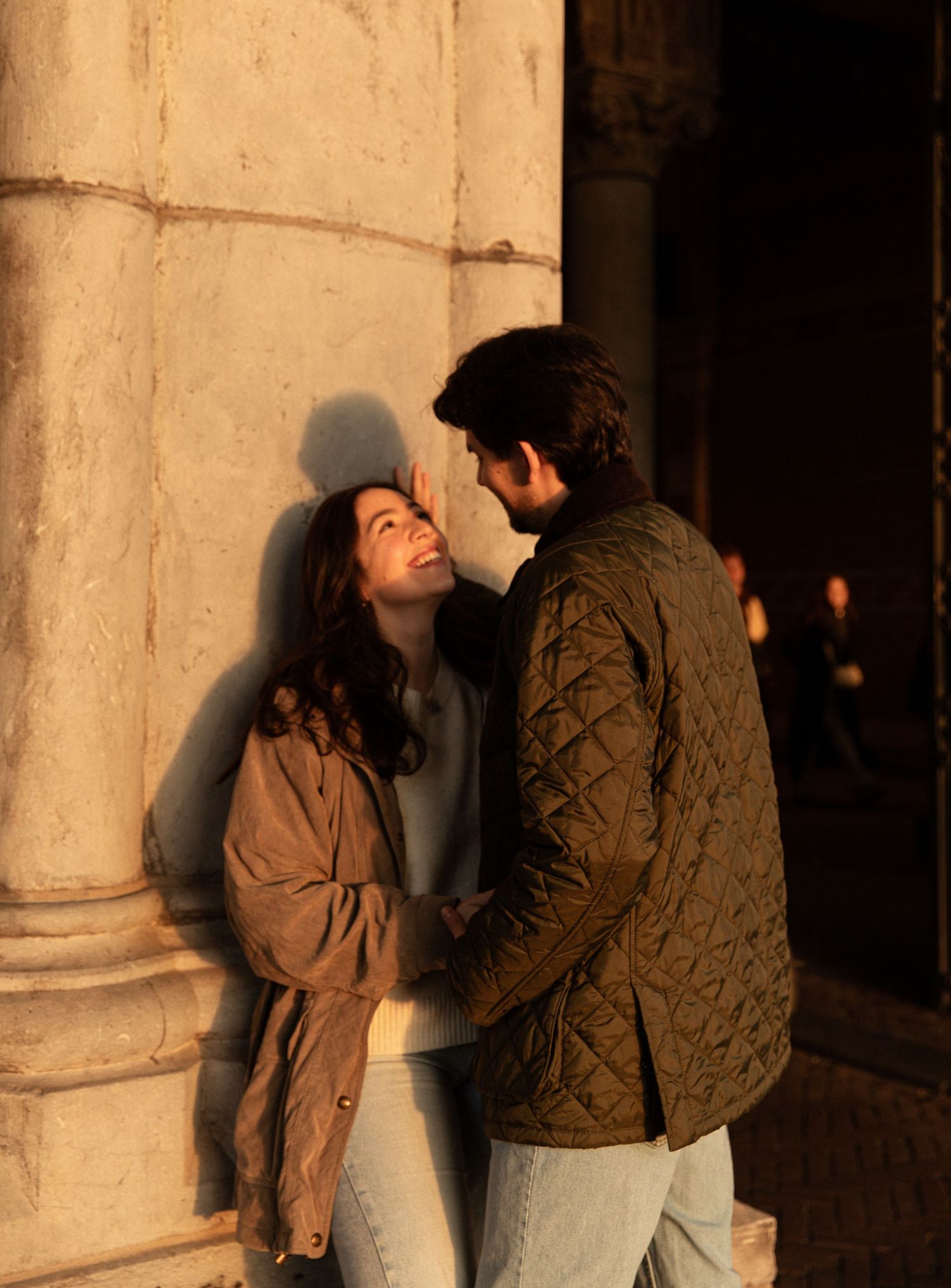Romantic couple photos against a light-colored pillar with dramatic shadows.