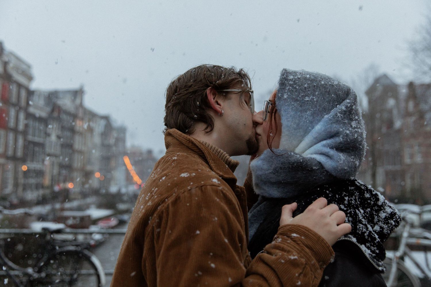 Snowy winter scene in Amsterdam with falling snow and historic architecture.