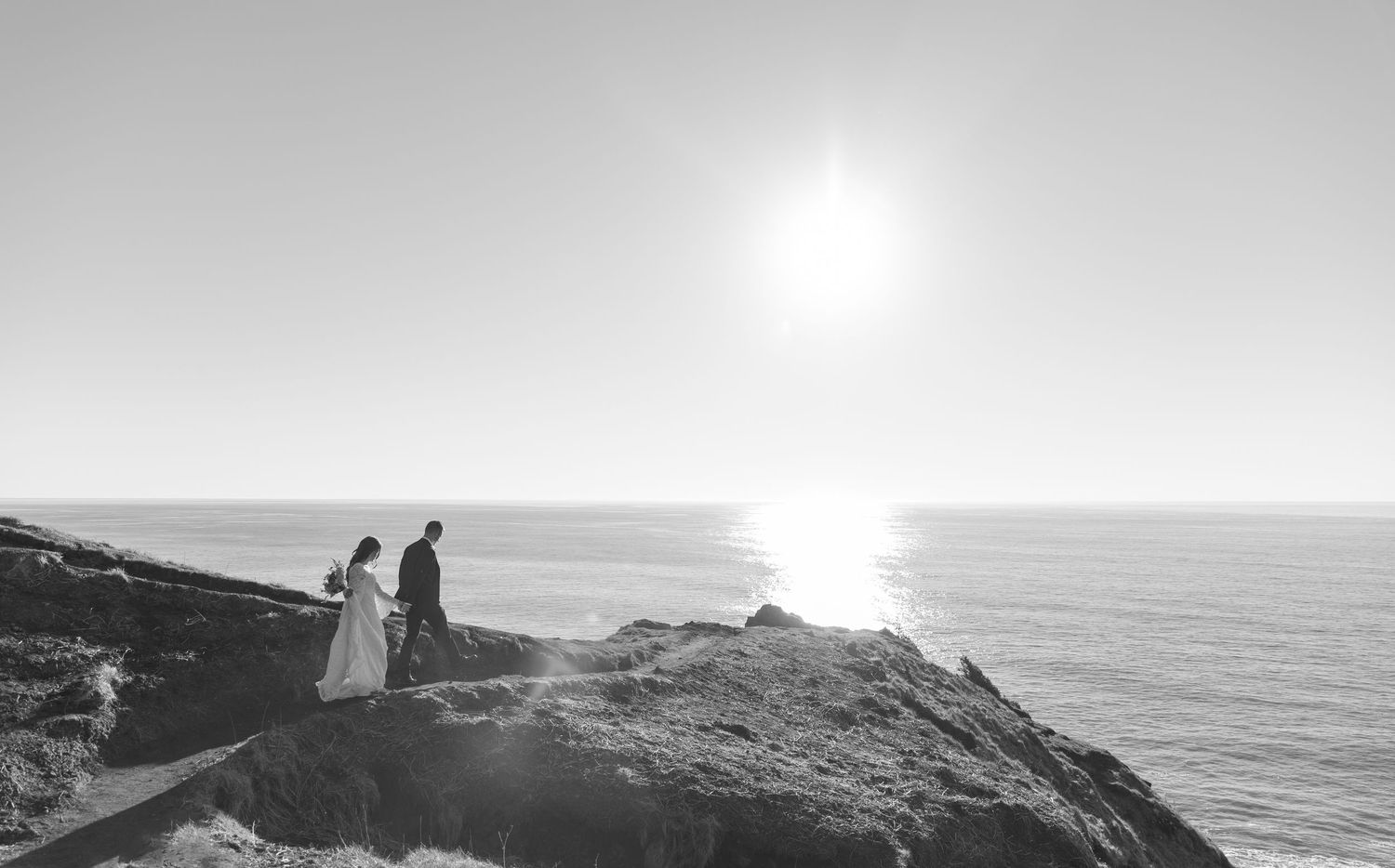 A scenic coastal landscape with a lighthouse perched atop rugged cliffs overlooking the ocean at sunset.