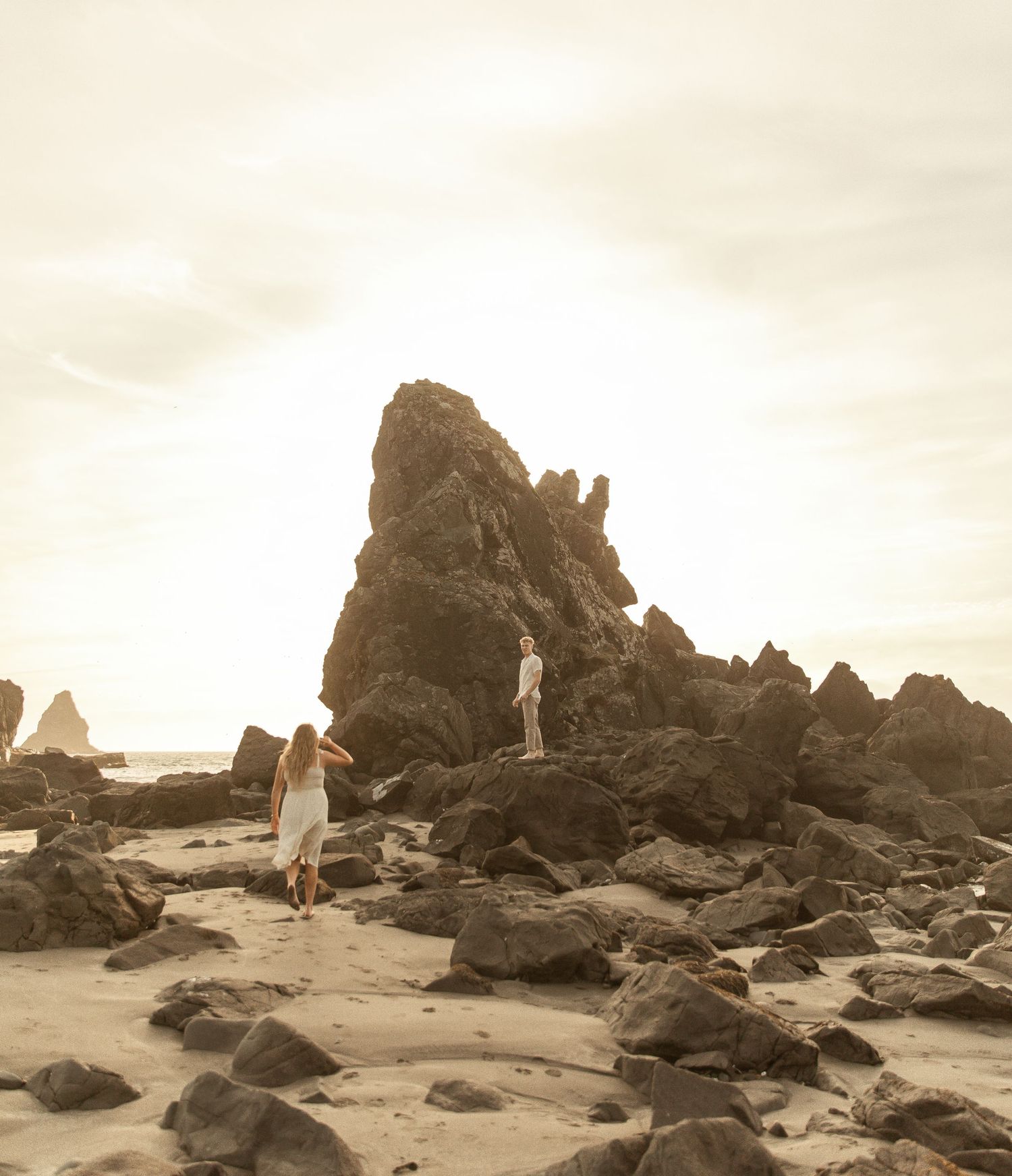 A series of sepia-toned beach photos showing a figure walking among dramatic coastal rock formations at sunset.