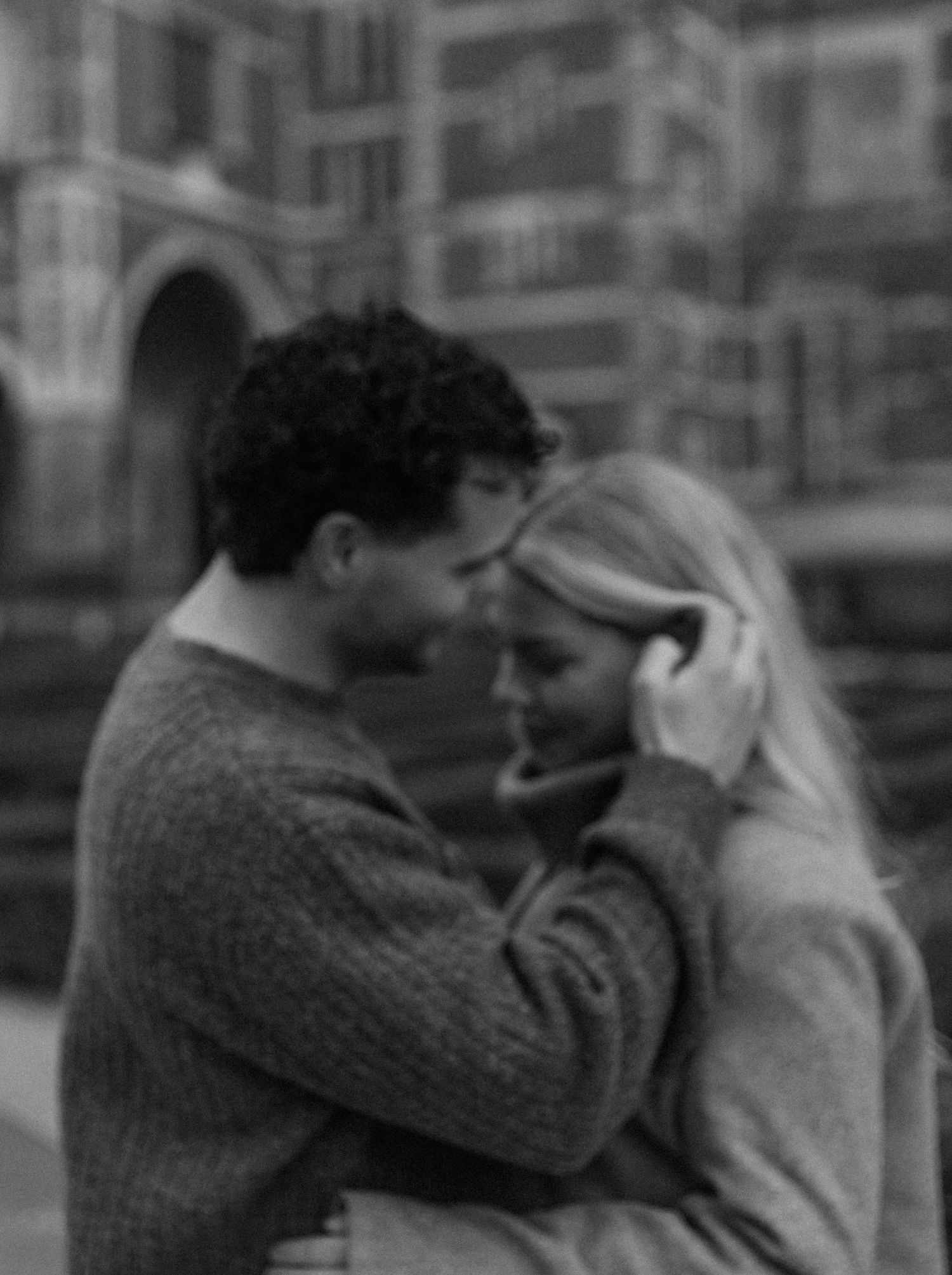 A black and white sequence of four frames showing two people in an embrace, captured in a romantic vintage style.
