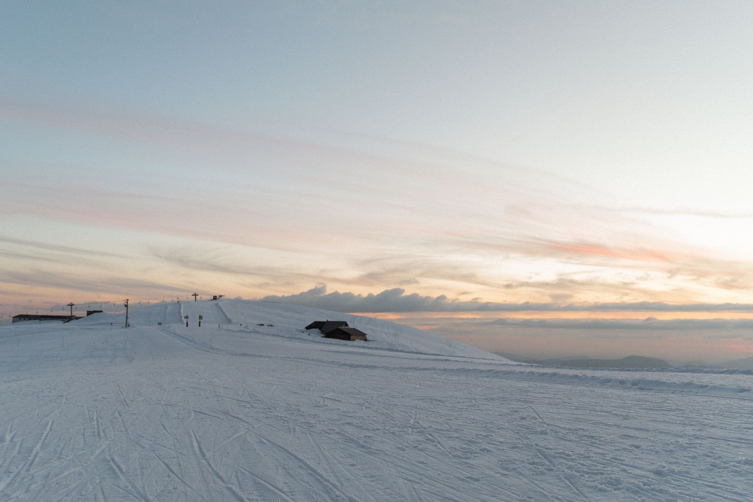 A scenic panoramic view of snow-covered mountains and a colorful sunset sky over a winter landscape.