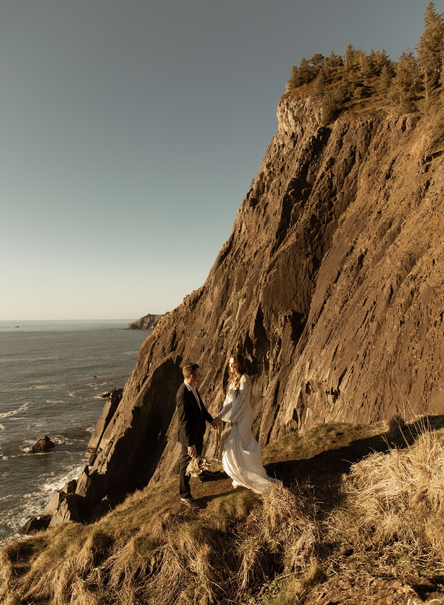 Scenic wedding photography on steep coastal cliffs with panoramic ocean views.